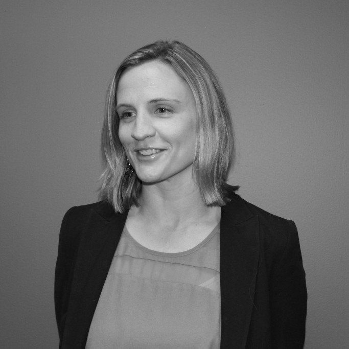 A black and white photo of a woman wearing a jacket and smiling.