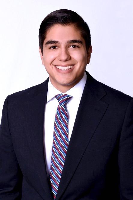 A man in a suit and tie is smiling for the camera