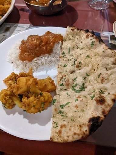 Plate with rice, curry, vegetable dish, and naan bread.