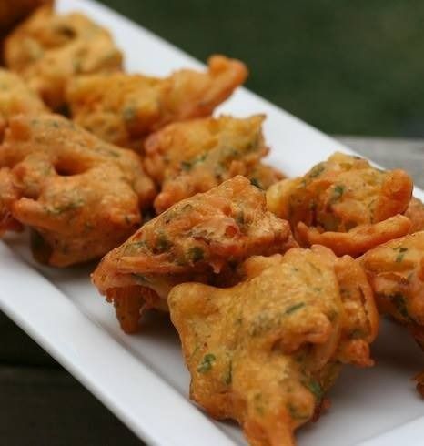 Golden-fried pakoras, a South Asian fritter, arranged on a white serving platter.