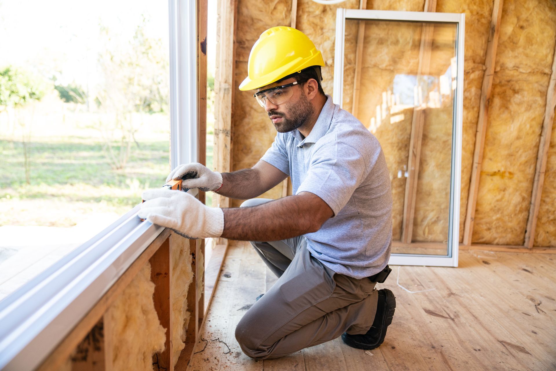 Window installation in wooden house under construction.