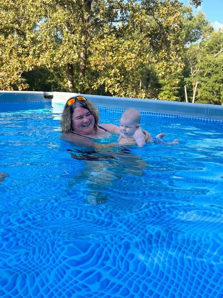 A woman is holding a baby in a swimming pool.