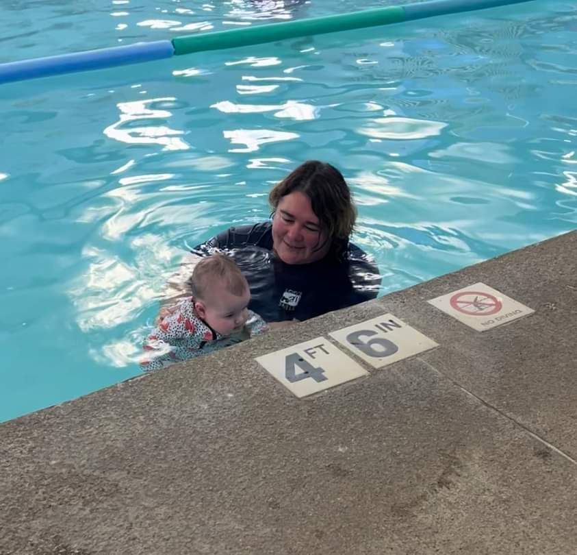 A woman is holding a baby in a swimming pool.