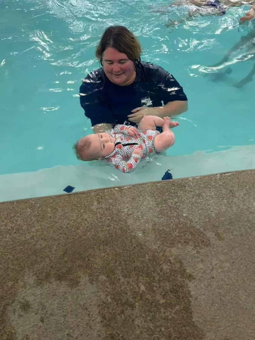 A woman is holding a baby in a swimming pool