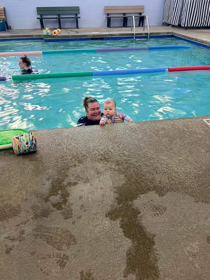 A woman is holding a baby in a swimming pool.
