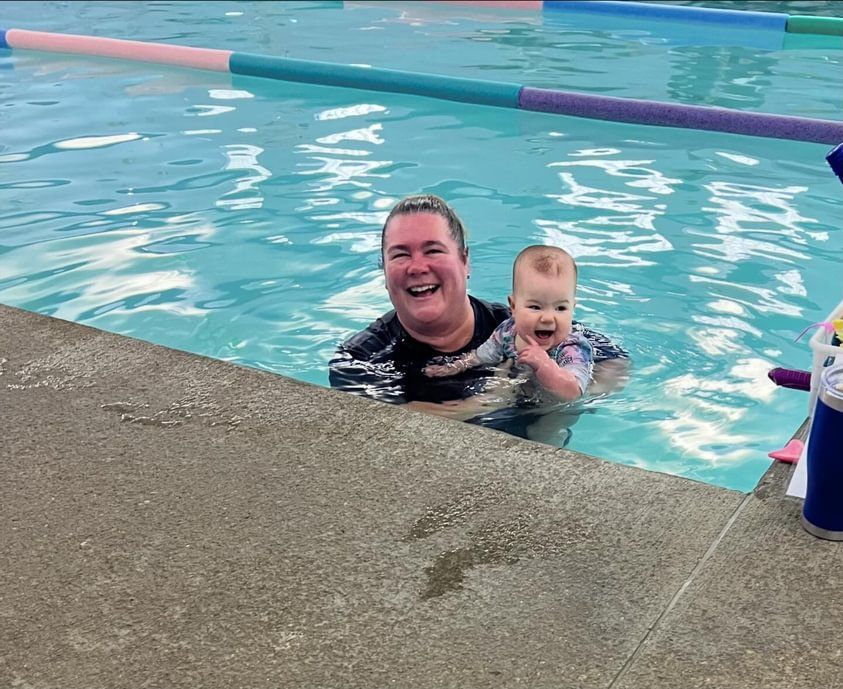 A man is holding a baby in a swimming pool.
