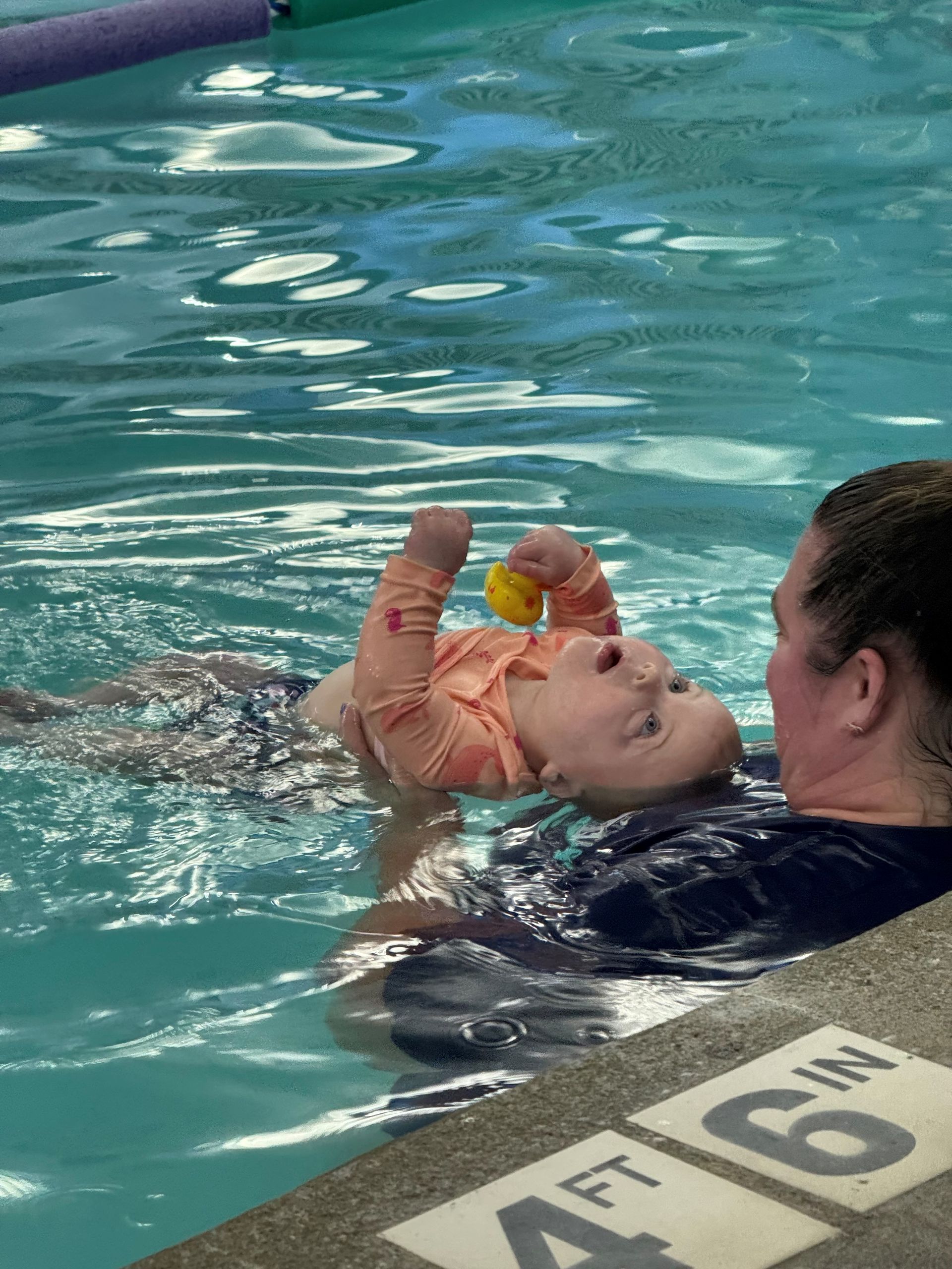 A woman is teaching a child how to swim in a pool.