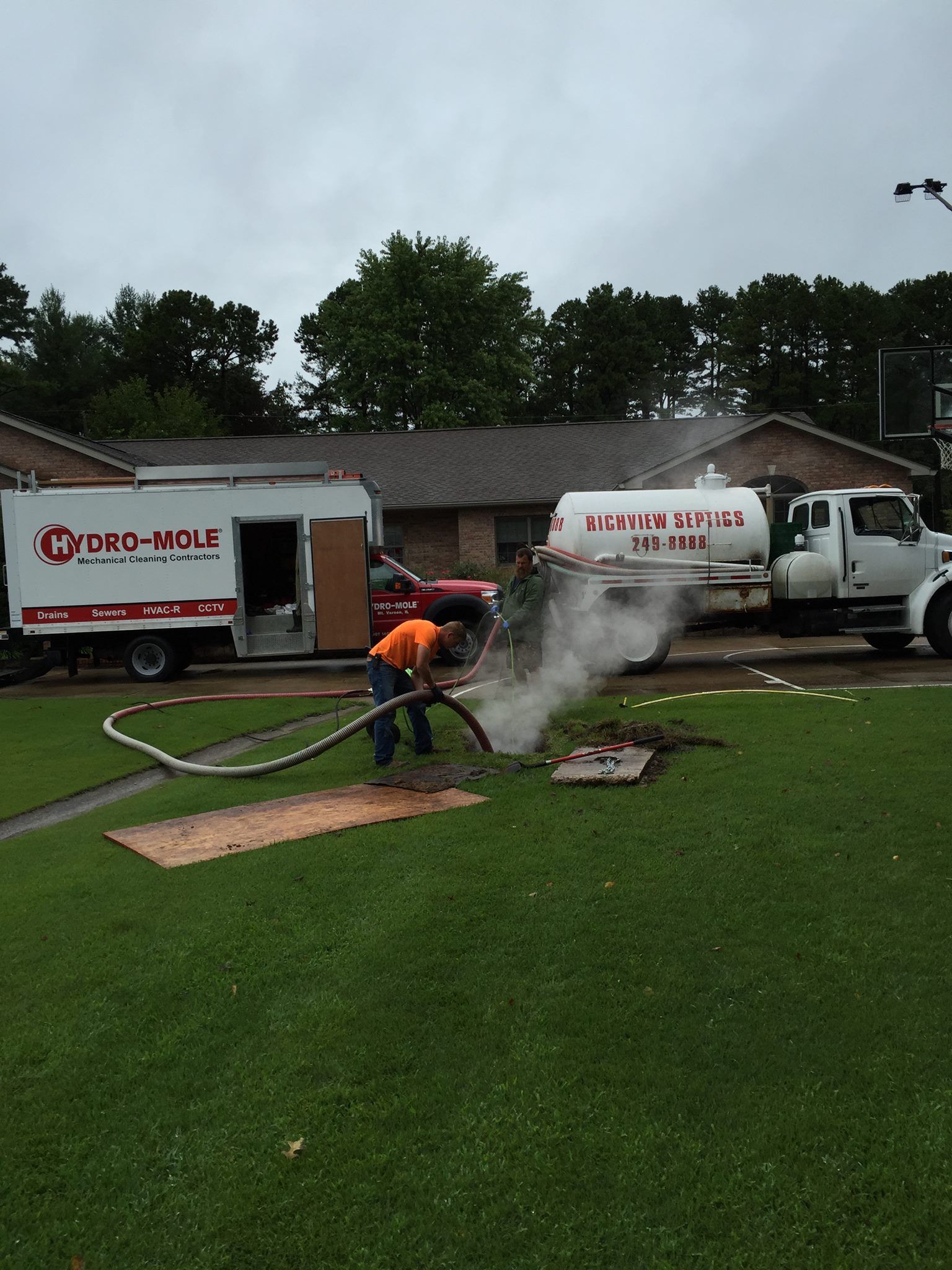 A man is working on a manhole cover in front of a ford truck.
