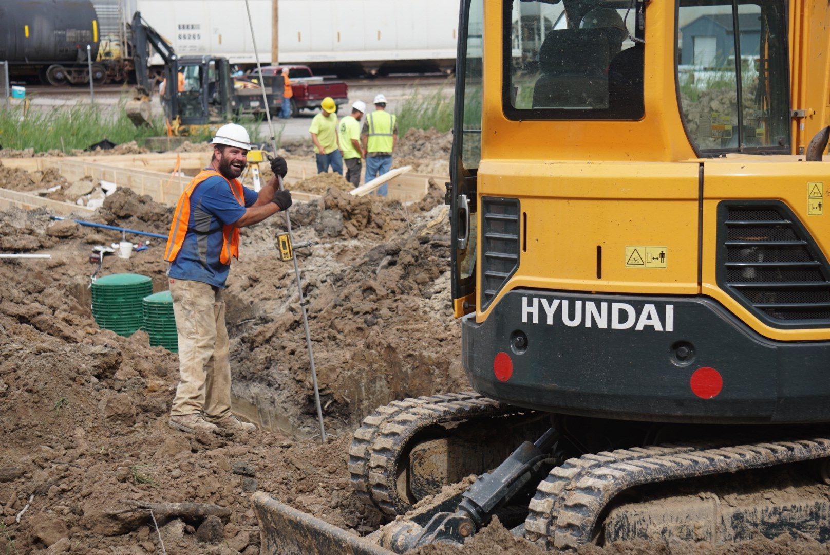 A man is standing in front of a yellow hyundai excavator.