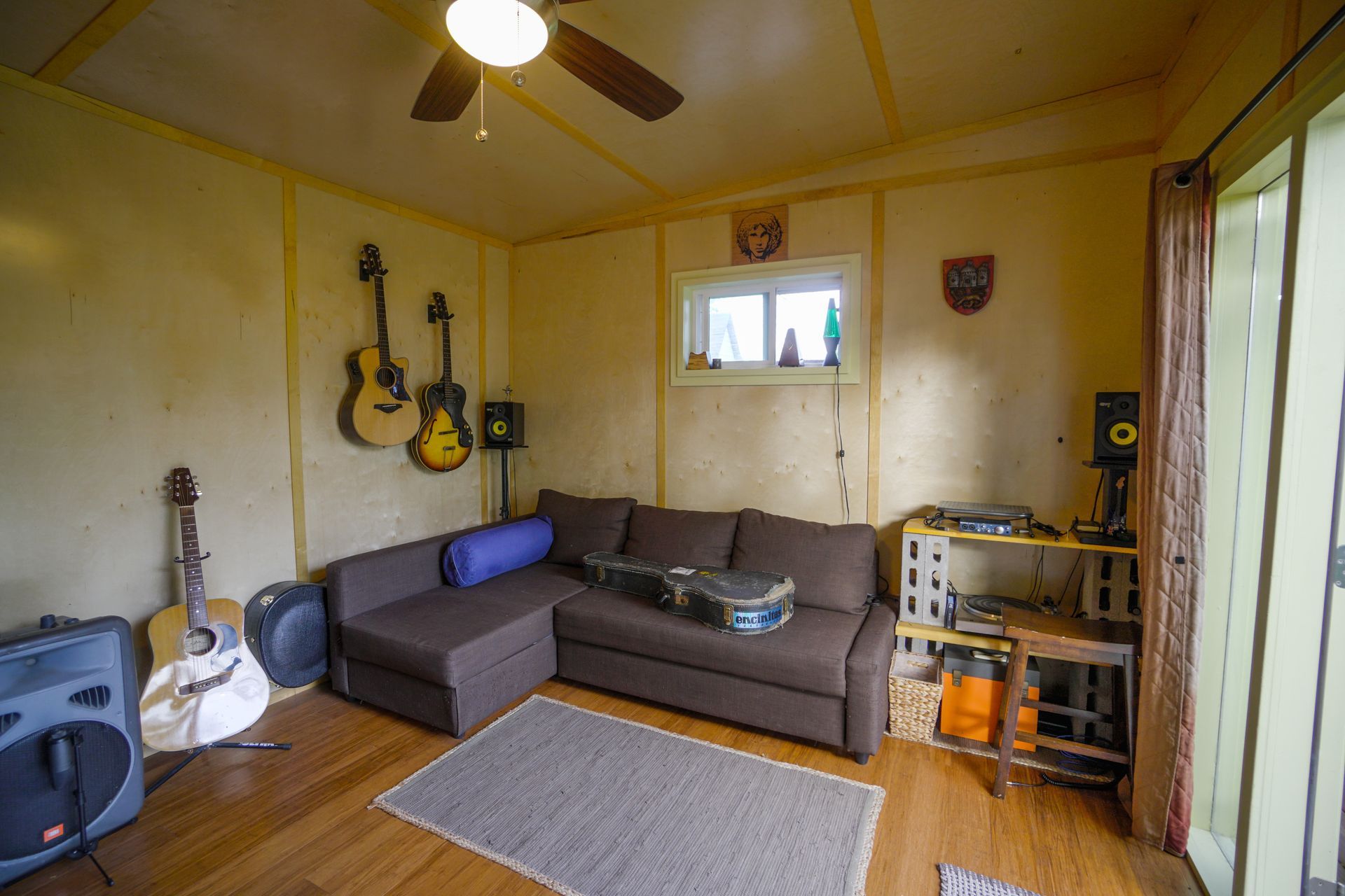 Cozy music room with guitars, a sofa, and audio equipment; brown and yellow tones.