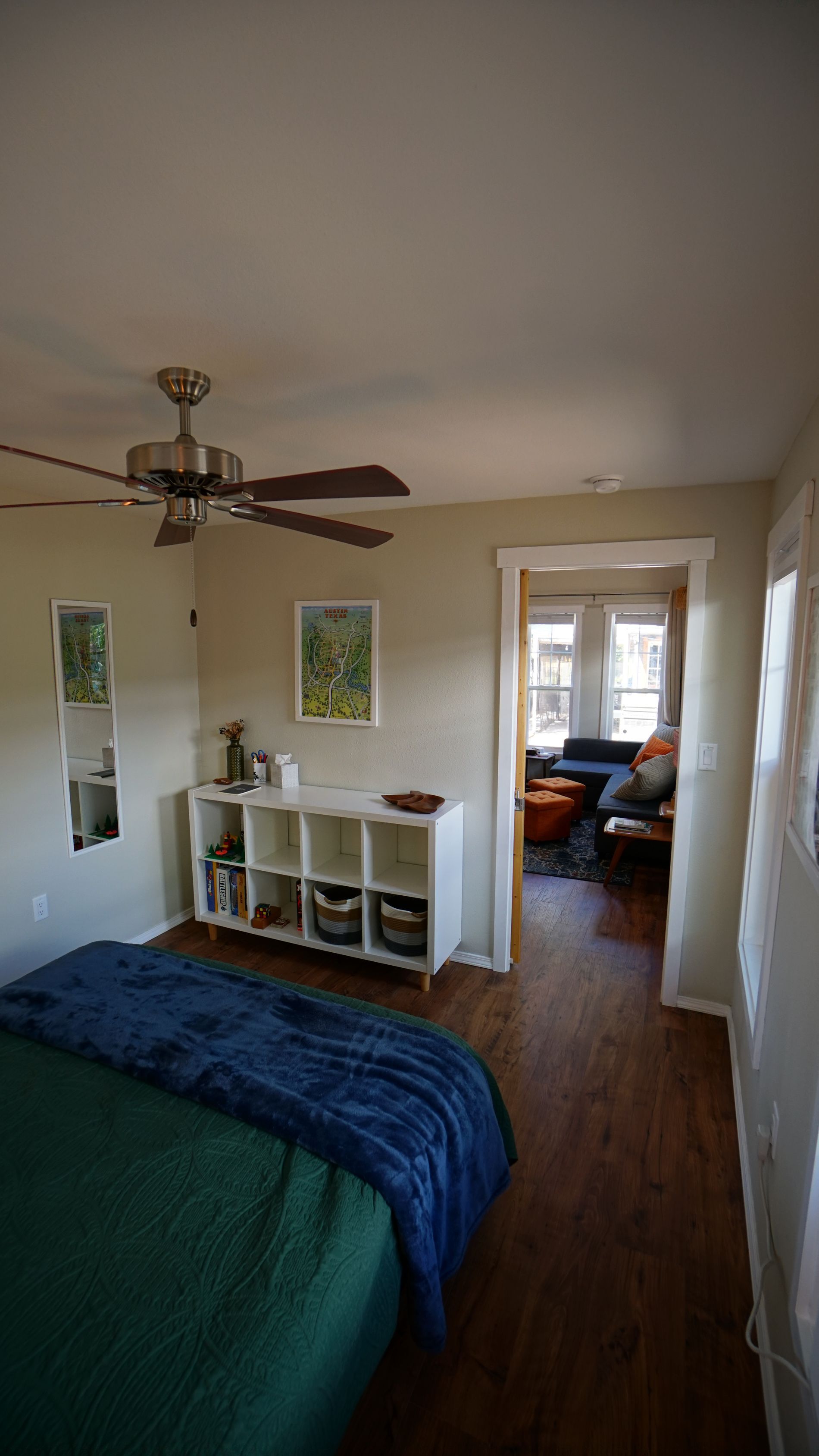 Bedroom with bed, shelving unit, and doorway leading to another room.