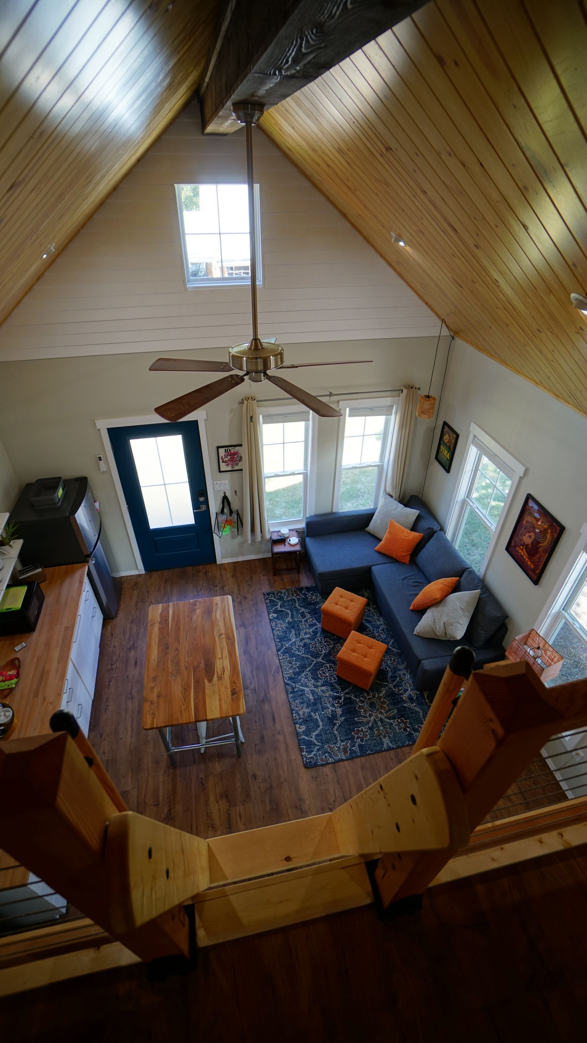 Overhead view of a living room with a blue sectional sofa, orange pillows, and a wooden coffee table.