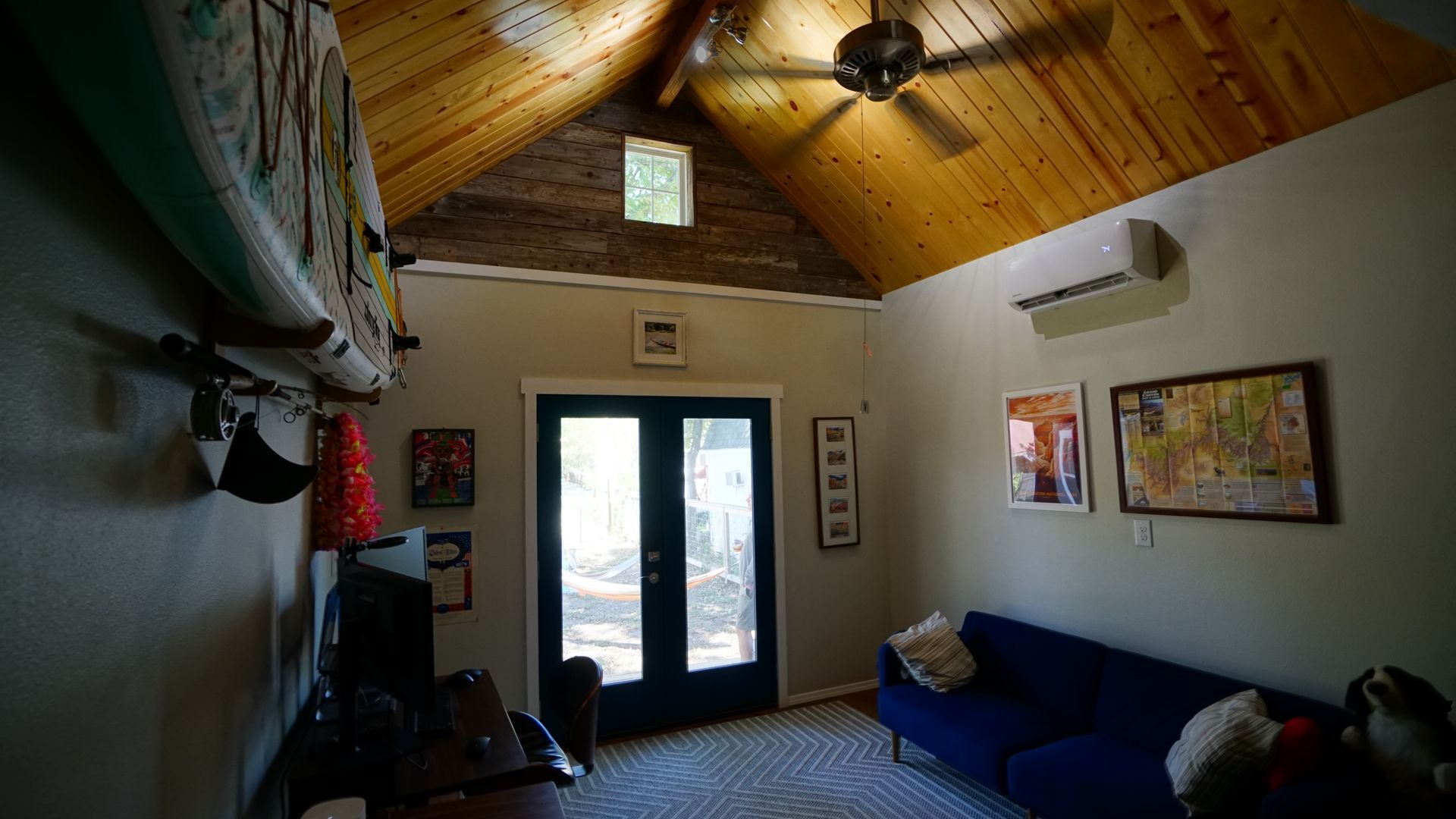 Interior room with wood-paneled ceiling, blue sofa, and French doors leading outside.