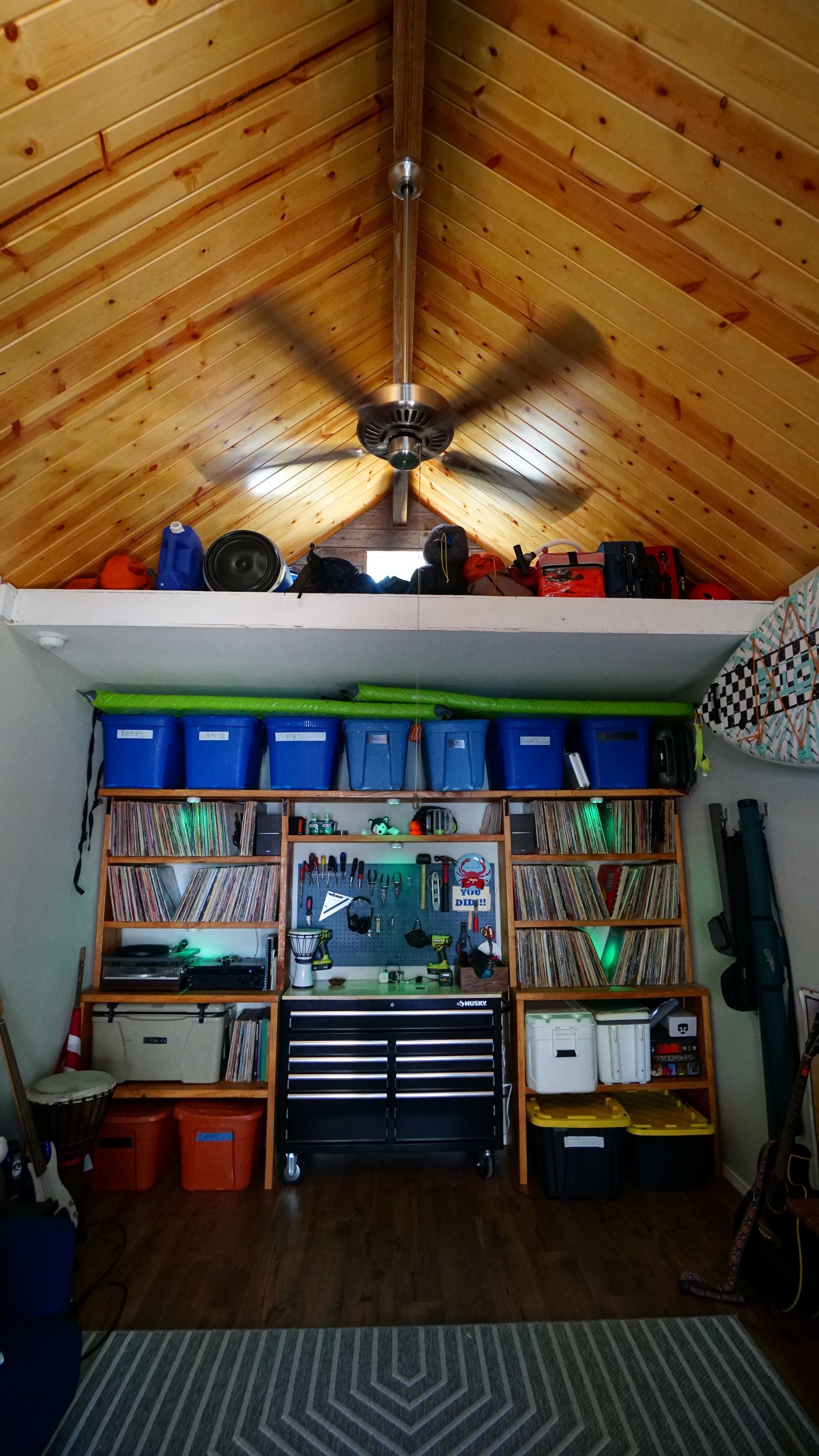 Workshop interior with tool storage, blue bins, and a ceiling fan.