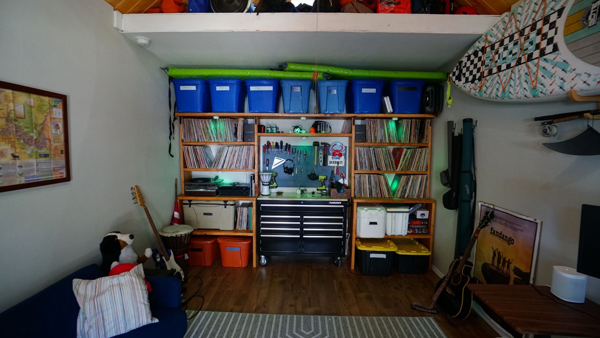 A small storage space with shelves and bins, a workbench, and a couch, containing various items.
