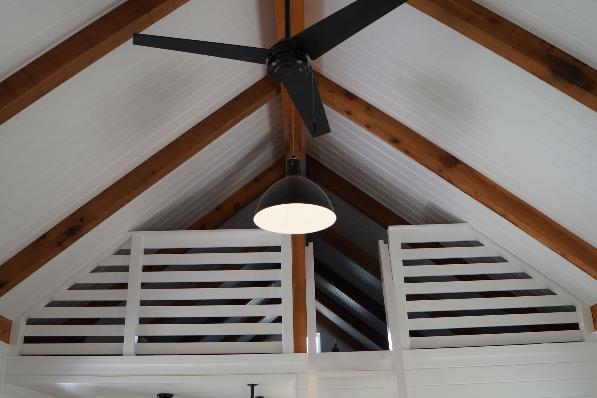 Interior view with wooden beams, white paneling, ceiling fan, and pendant light.