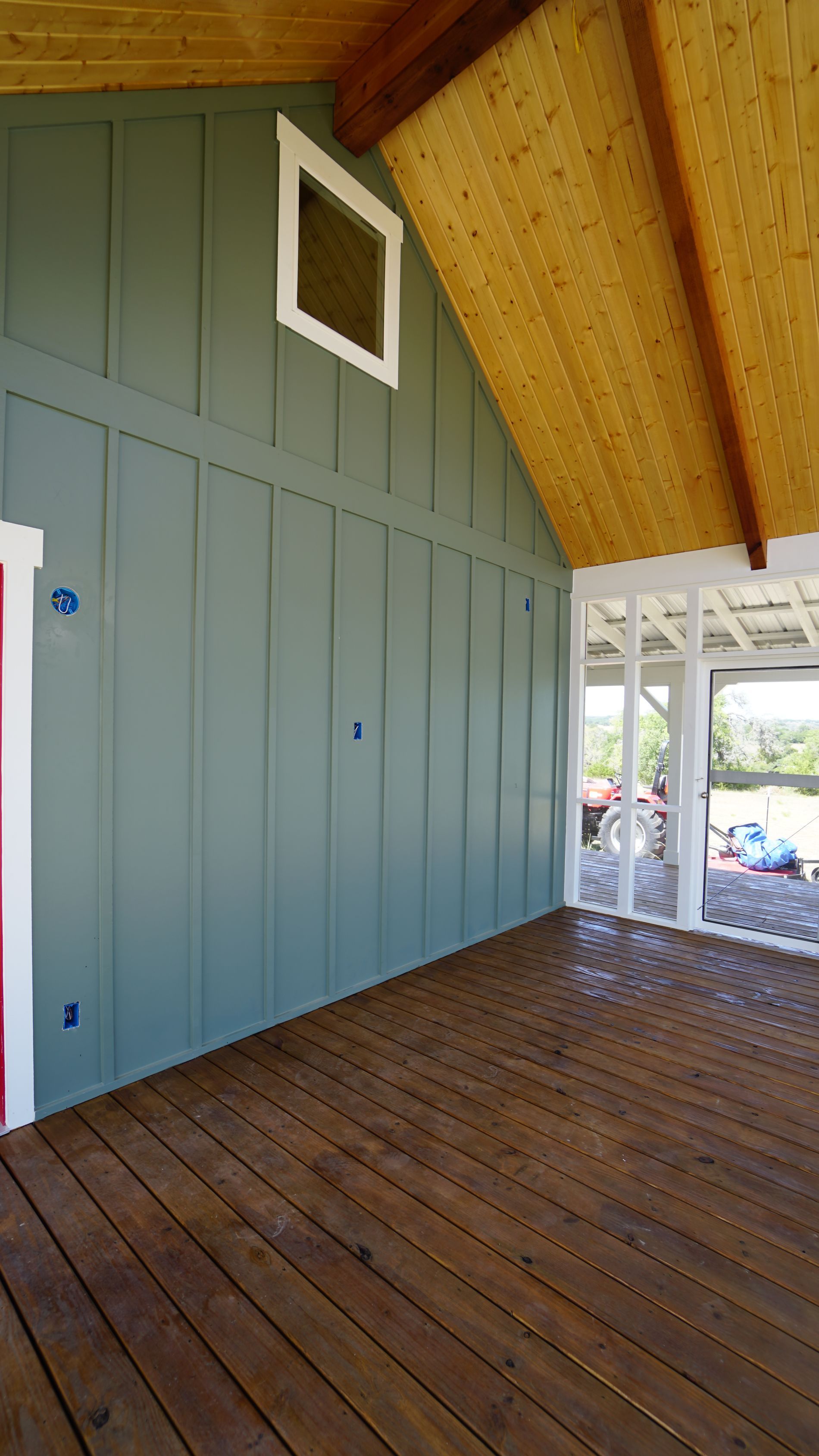 Wooden porch with blue siding, a small window, and a wood ceiling.
