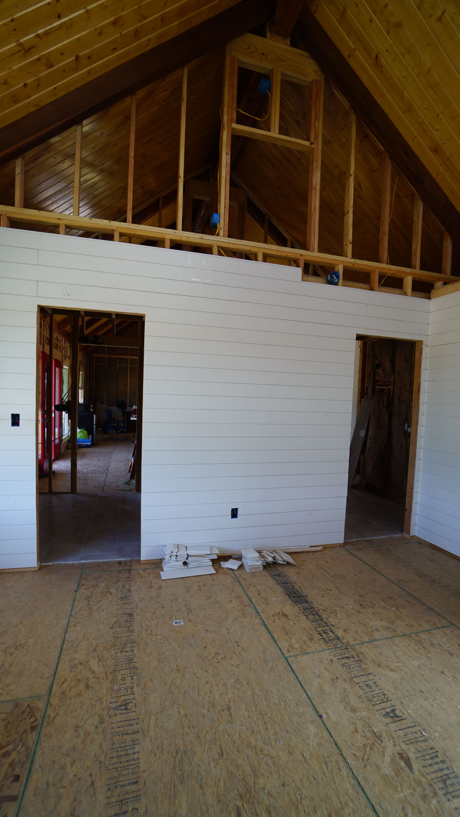 Interior of a building under construction, with wooden framing and white-paneled walls.