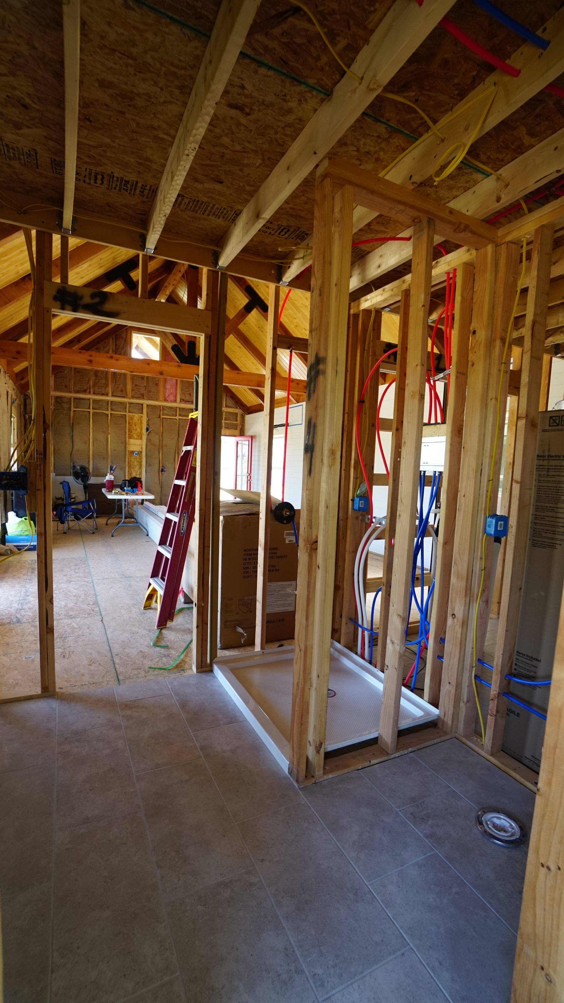 Interior framing of a house under construction; shower stall, exposed beams, and concrete floor.