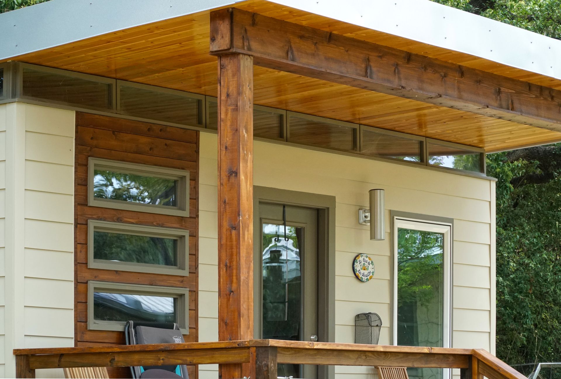 Modern building with a wooden porch, windows, and a light-colored exterior.