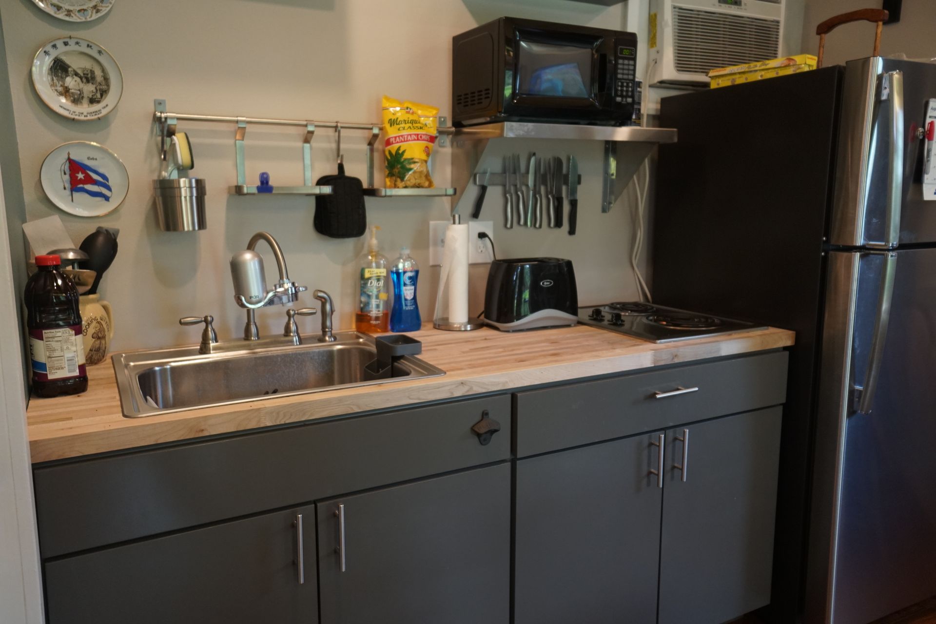 Small kitchen with stainless steel appliances, grey cabinets, and wood countertops.