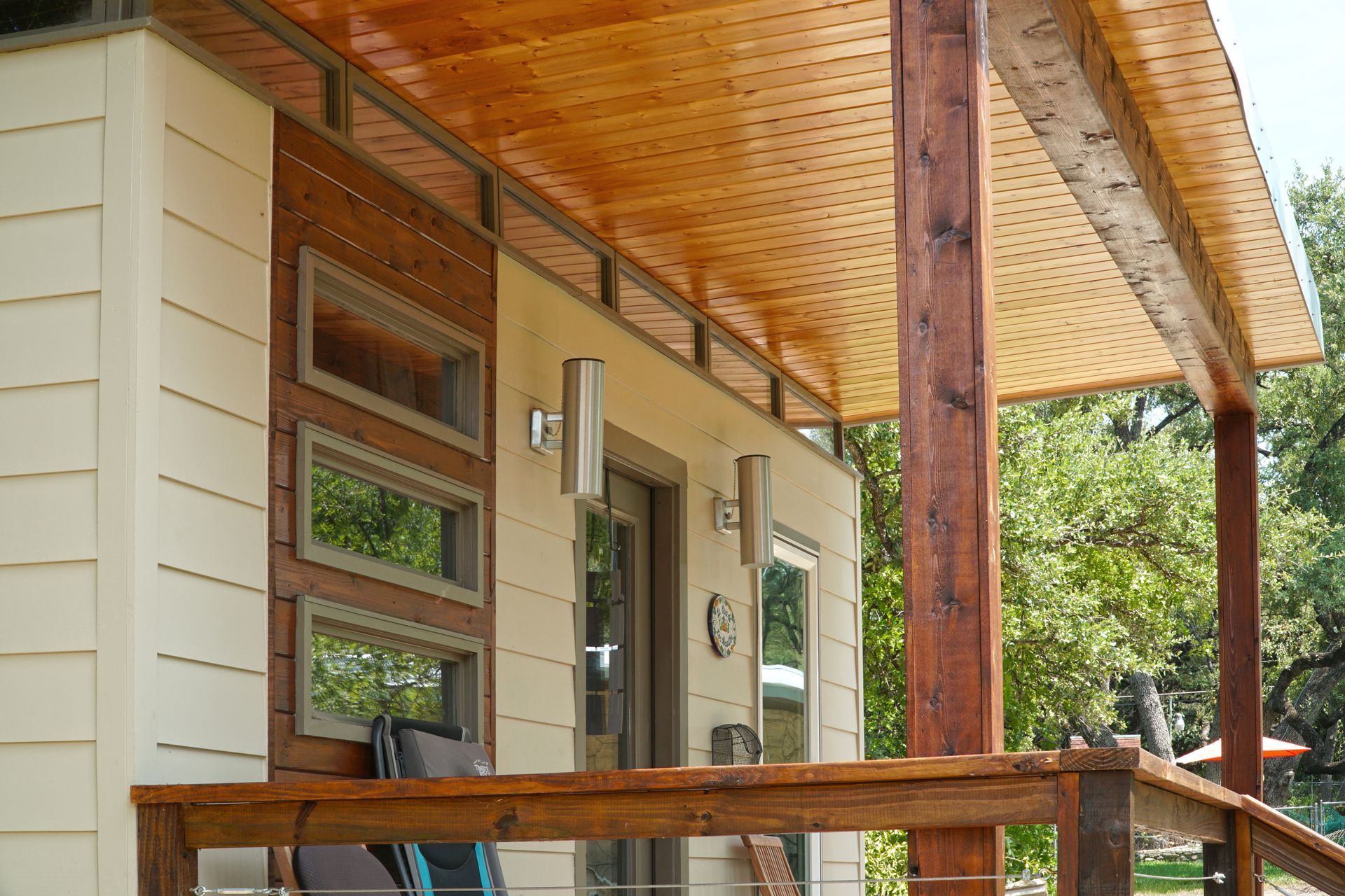 Tiny house exterior with wooden porch and siding. Beige walls, wood trim, and a cedar ceiling.
