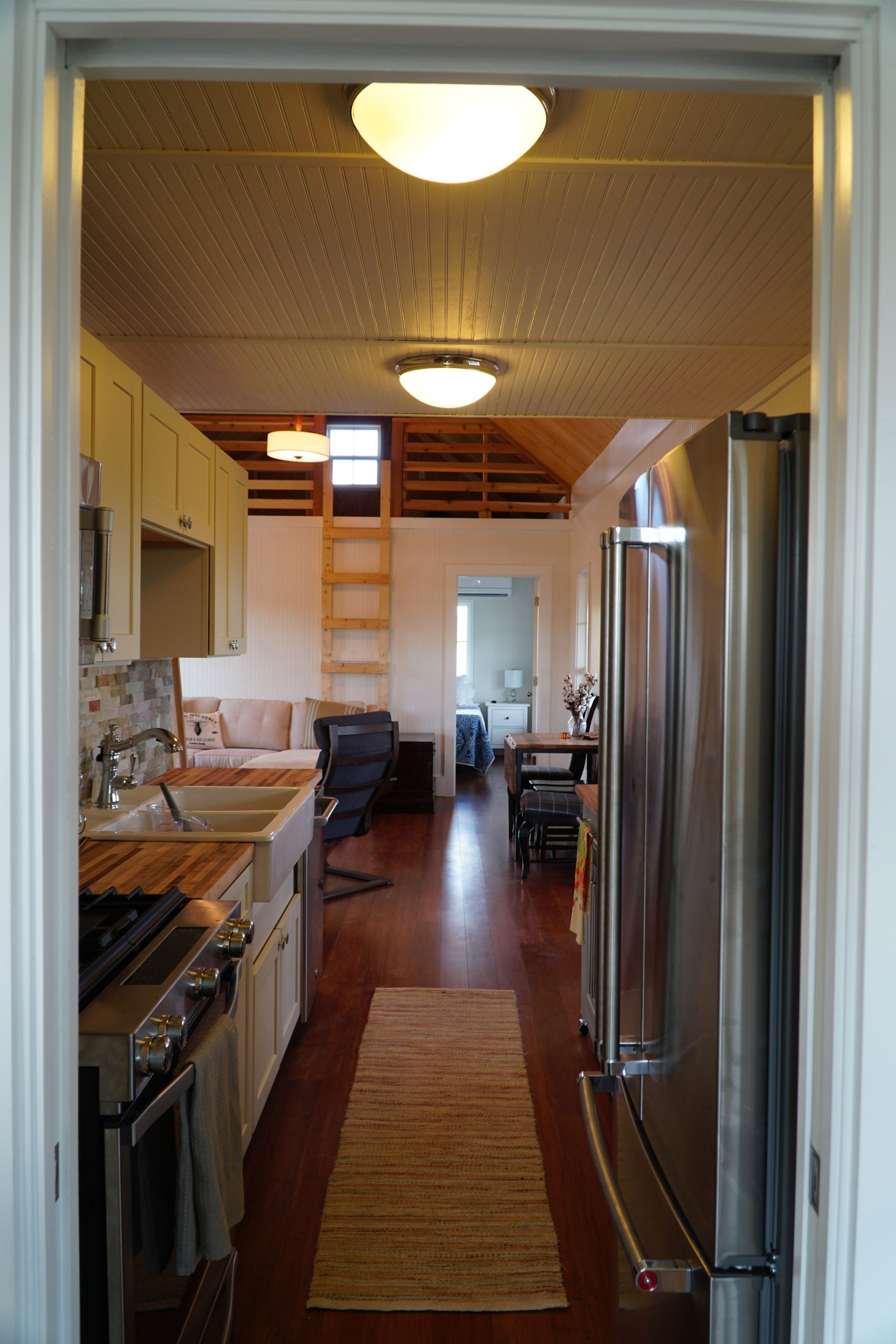 Kitchen interior with stainless steel refrigerator, white cabinets, and wood flooring.