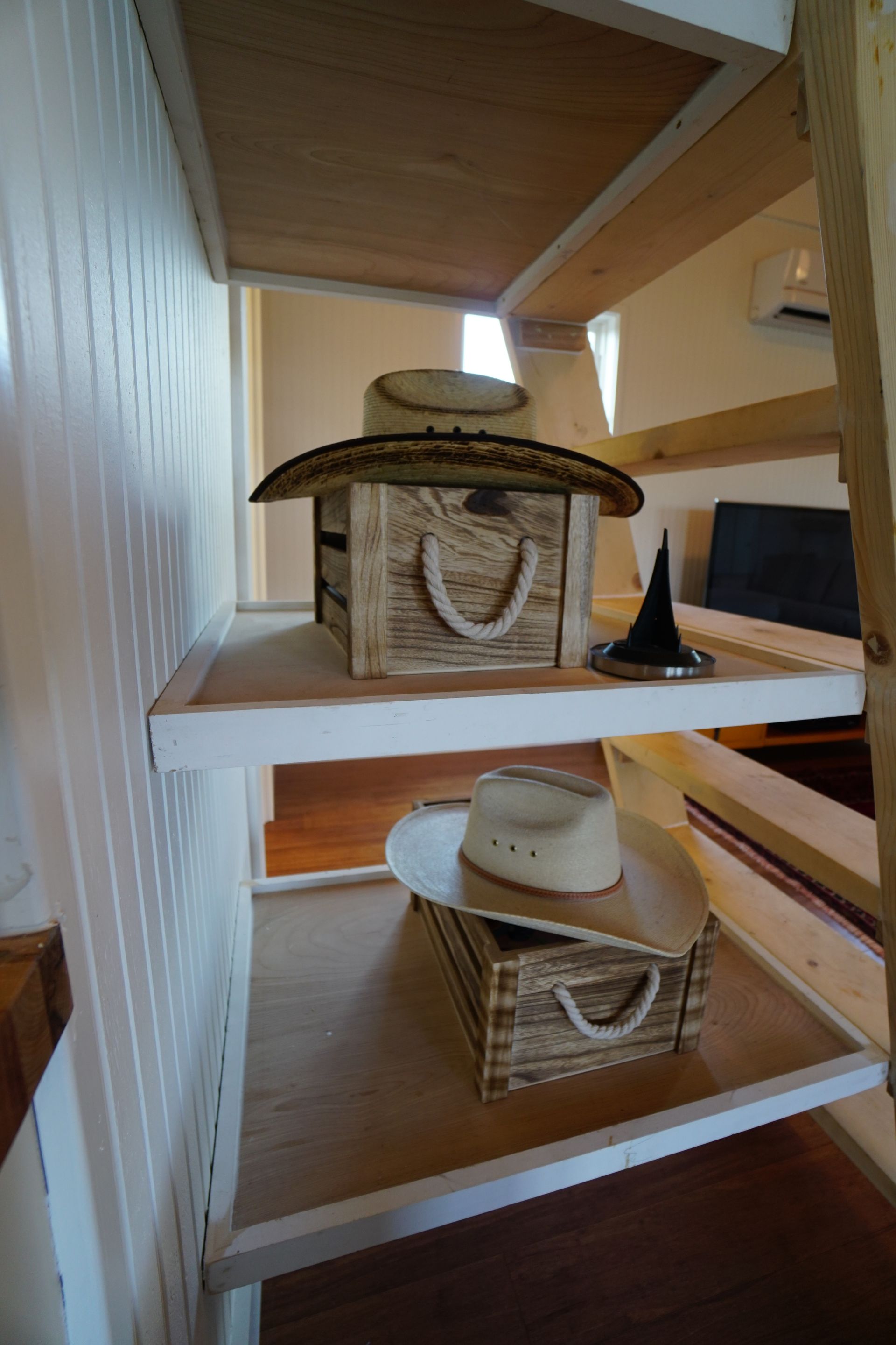 Wooden shelves with cowboy hats and a wicker box.