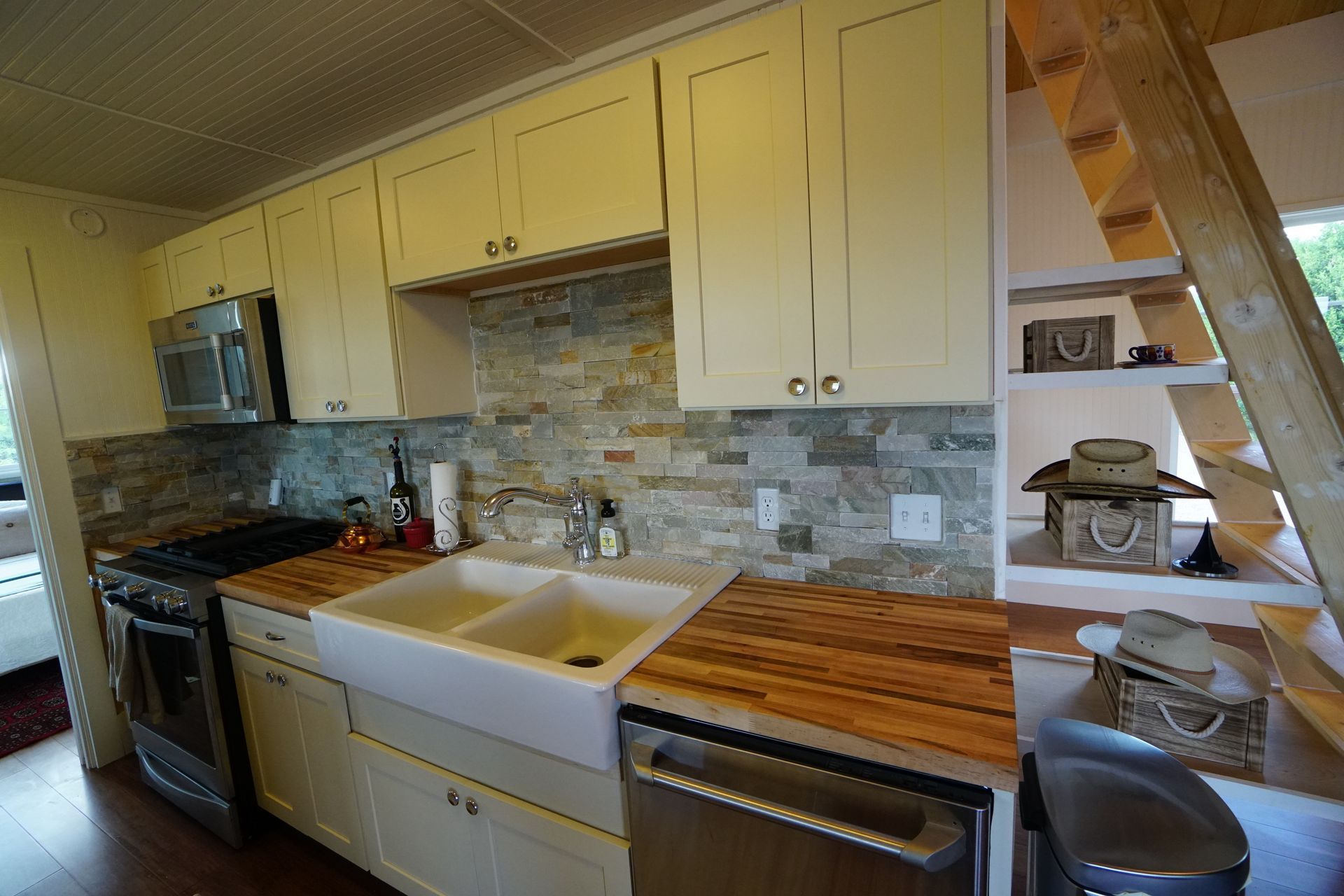 Kitchen with white cabinets, wood countertops, stone backsplash, and stainless steel appliances.