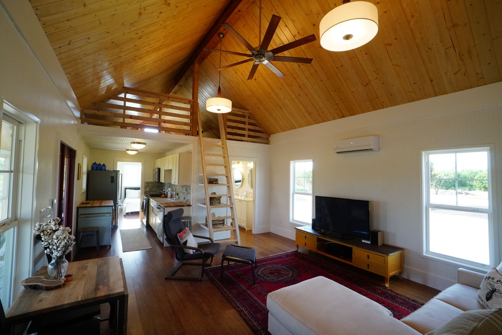 Cozy interior with wood ceiling, ladder to loft, TV, and living area.