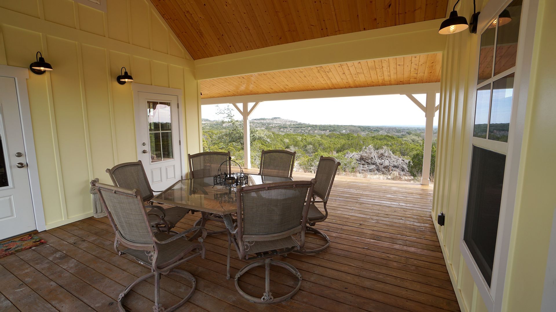 Covered outdoor patio with dining table and chairs, overlooking a scenic landscape.