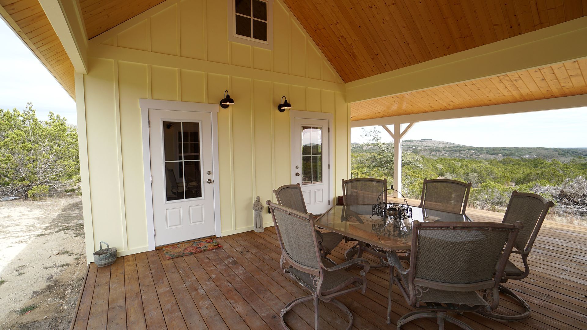 Yellow cottage porch with outdoor dining set and views.