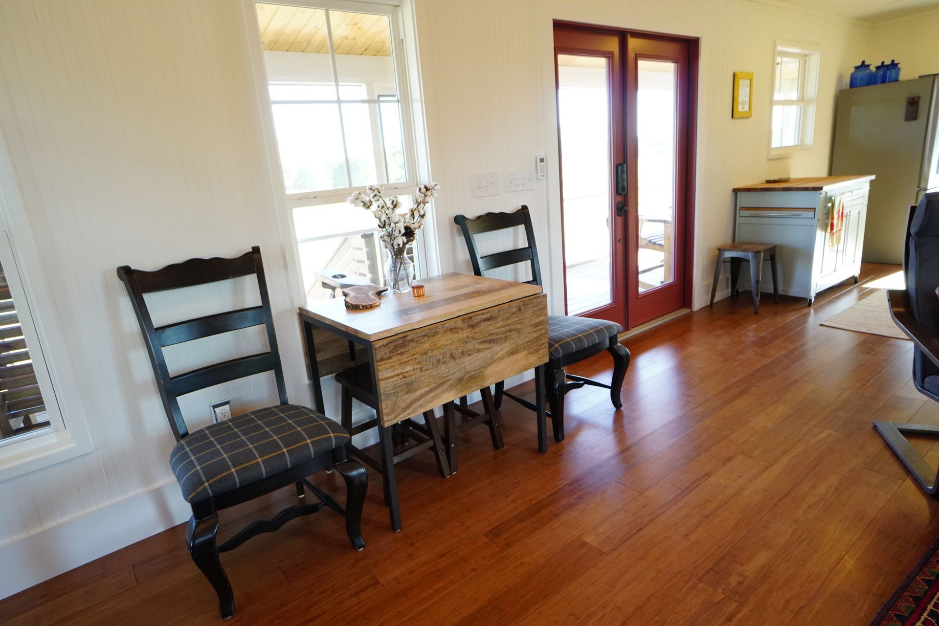 Dining area with wooden floor, table, and chairs. Window and double doors visible.