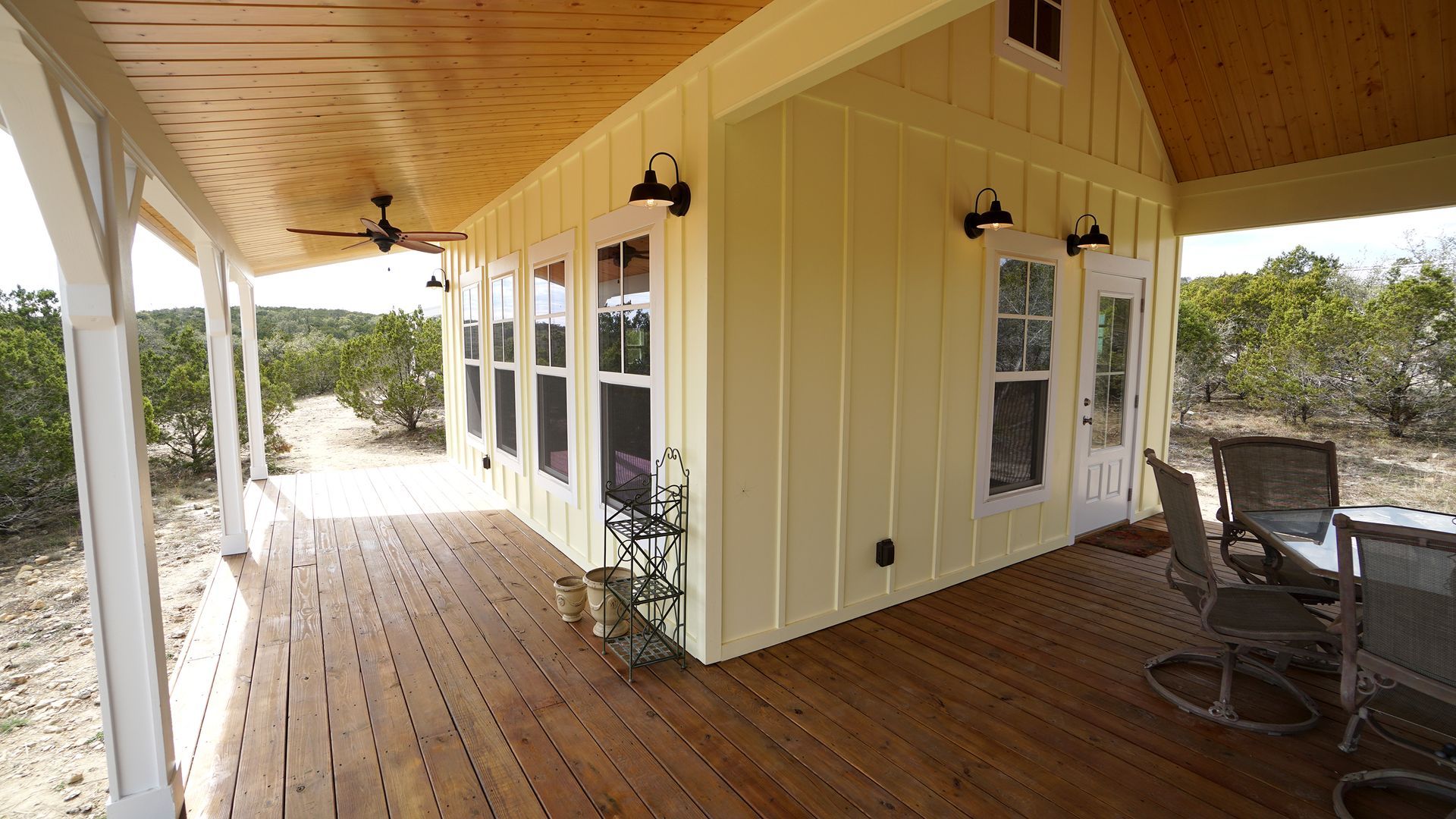 Yellow cabin with a covered porch, wooden deck, and outdoor furniture.