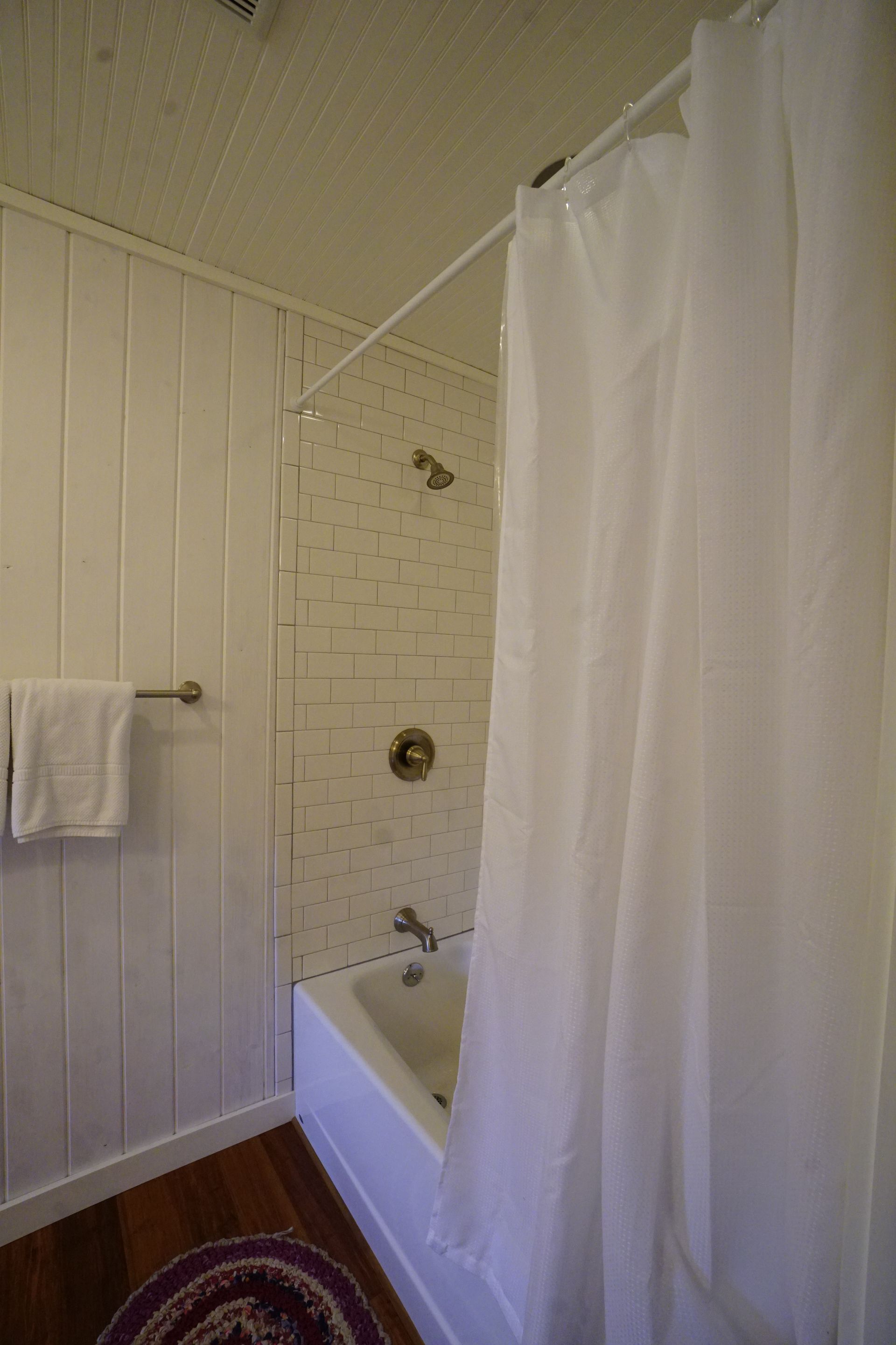 White bathroom with shower curtain, tub, and towel rack.