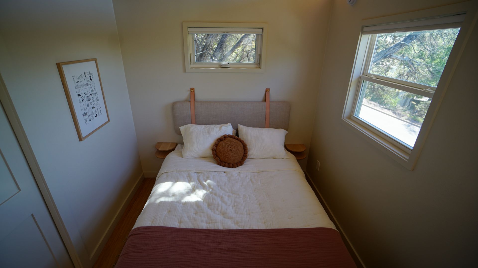 Small bedroom with a bed, two windows, and a framed art piece on the wall.