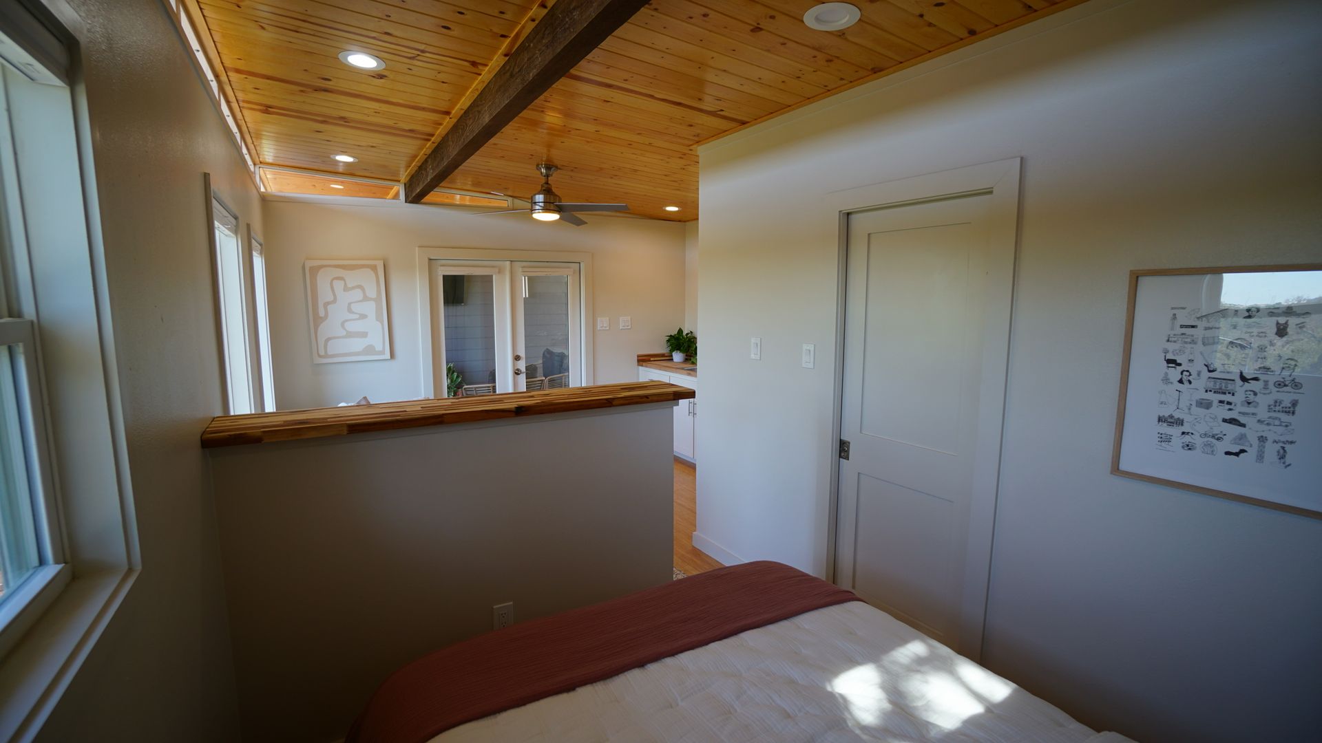 A spa room with a massage table, white walls, wood ceiling and a window.