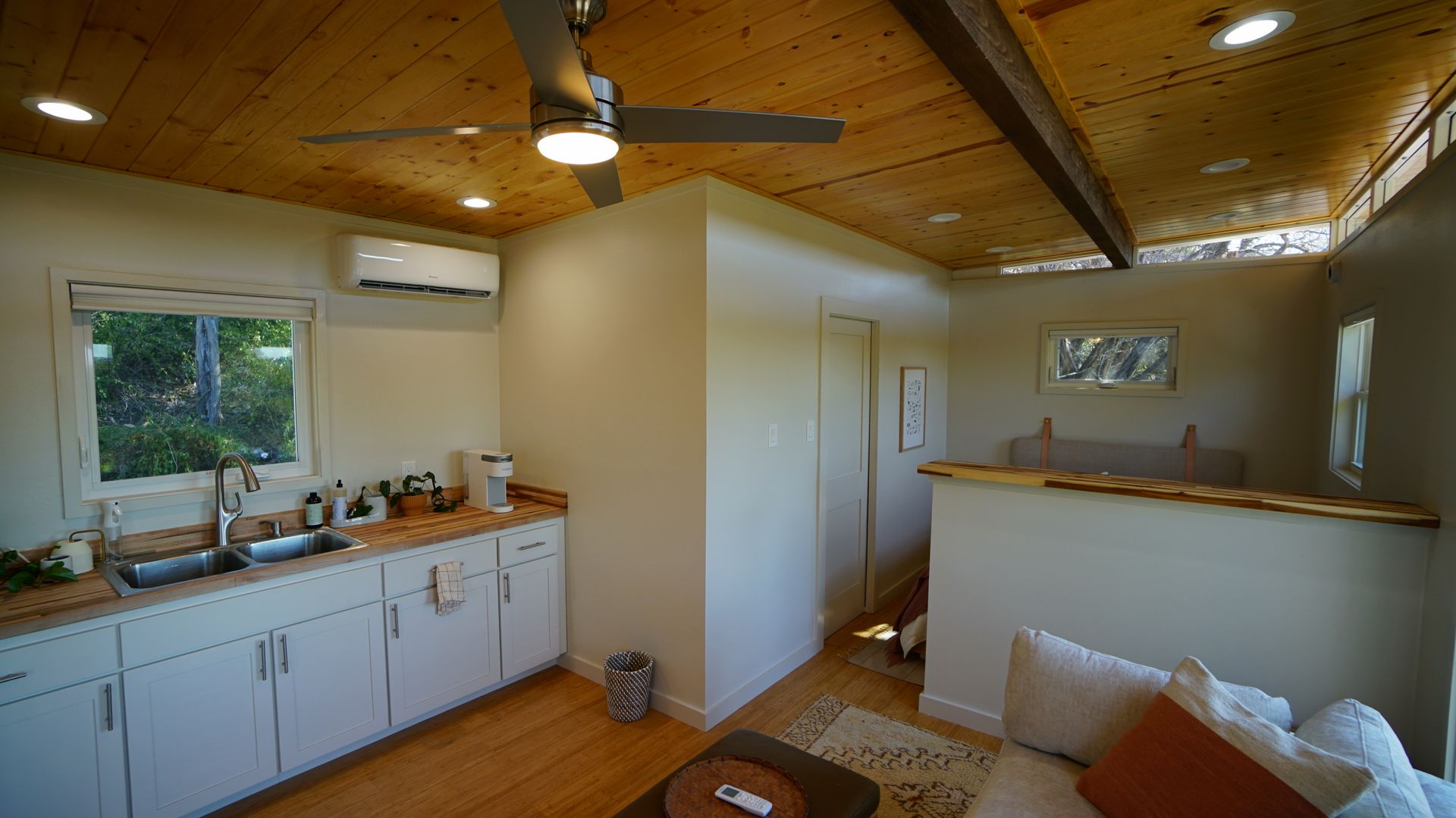 Interior of a small kitchen and living area, including a sink, cabinets, couch, and a loft.