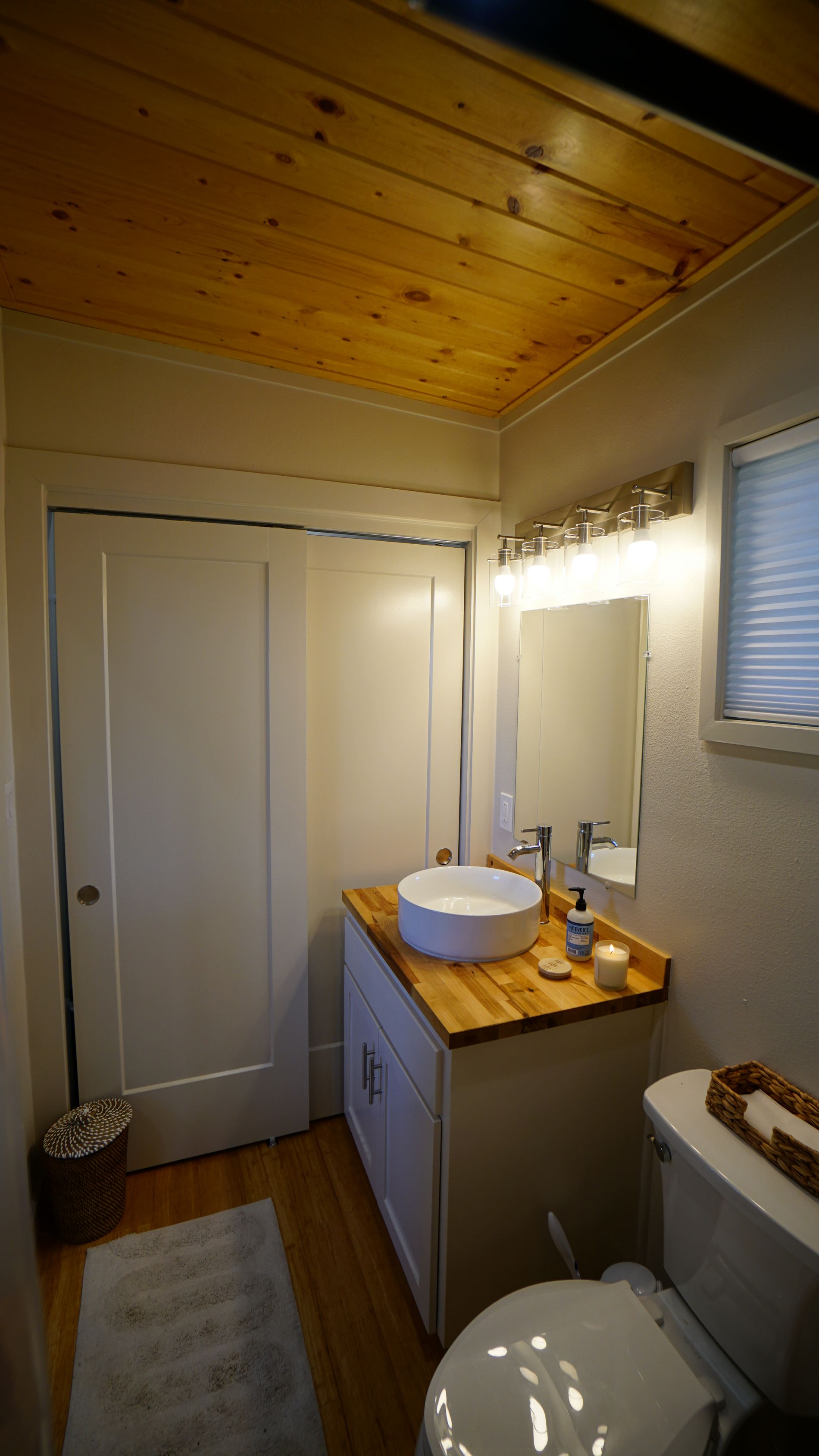 Bathroom with white vanity, round sink, toilet, and wooden ceiling.