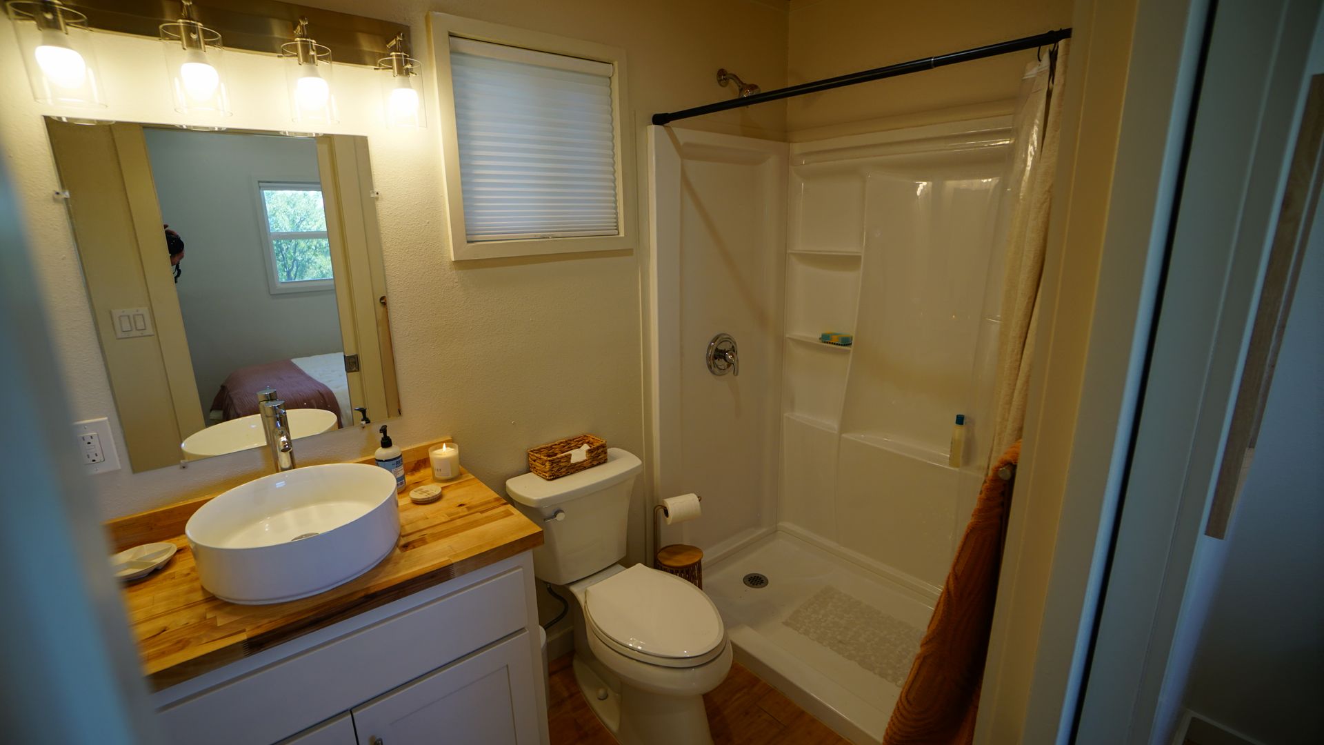 Bathroom with white sink on wood counter, shower, and toilet.