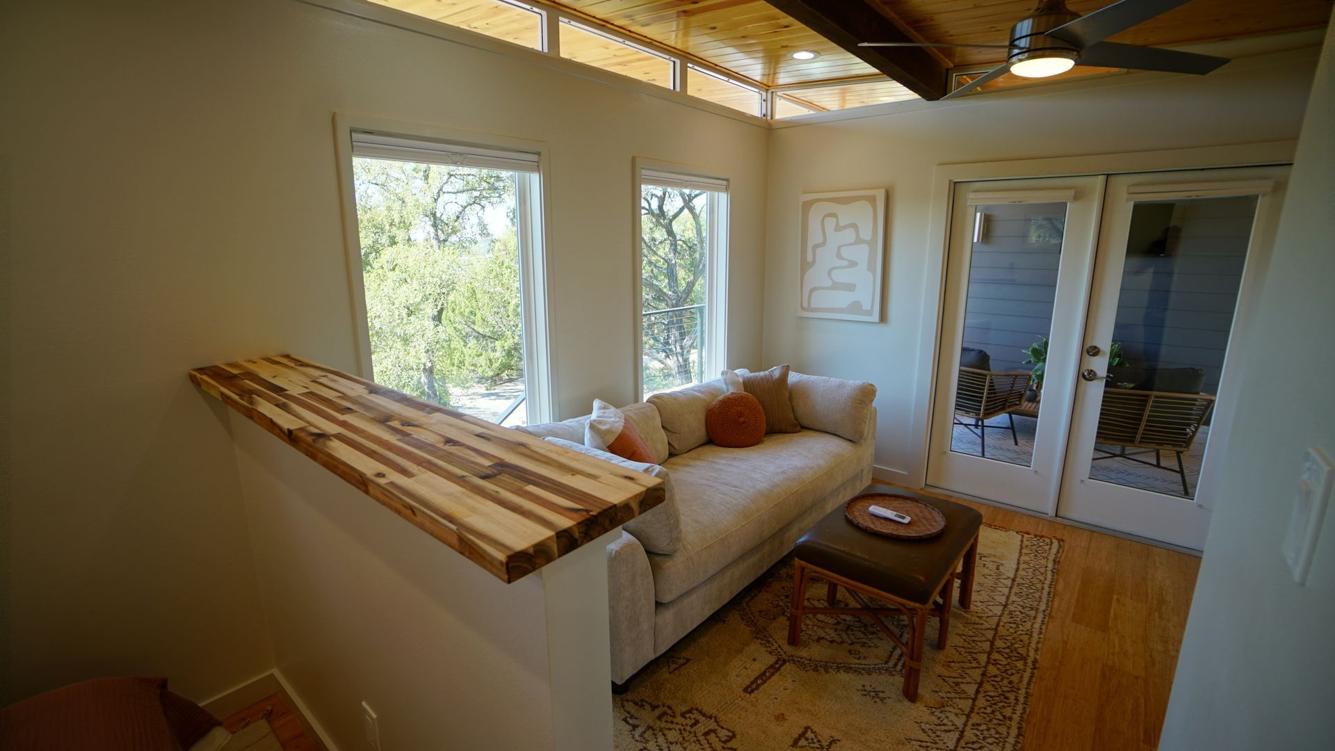 Cozy interior with a sofa, windows, and glass doors leading to an outdoor seating area.