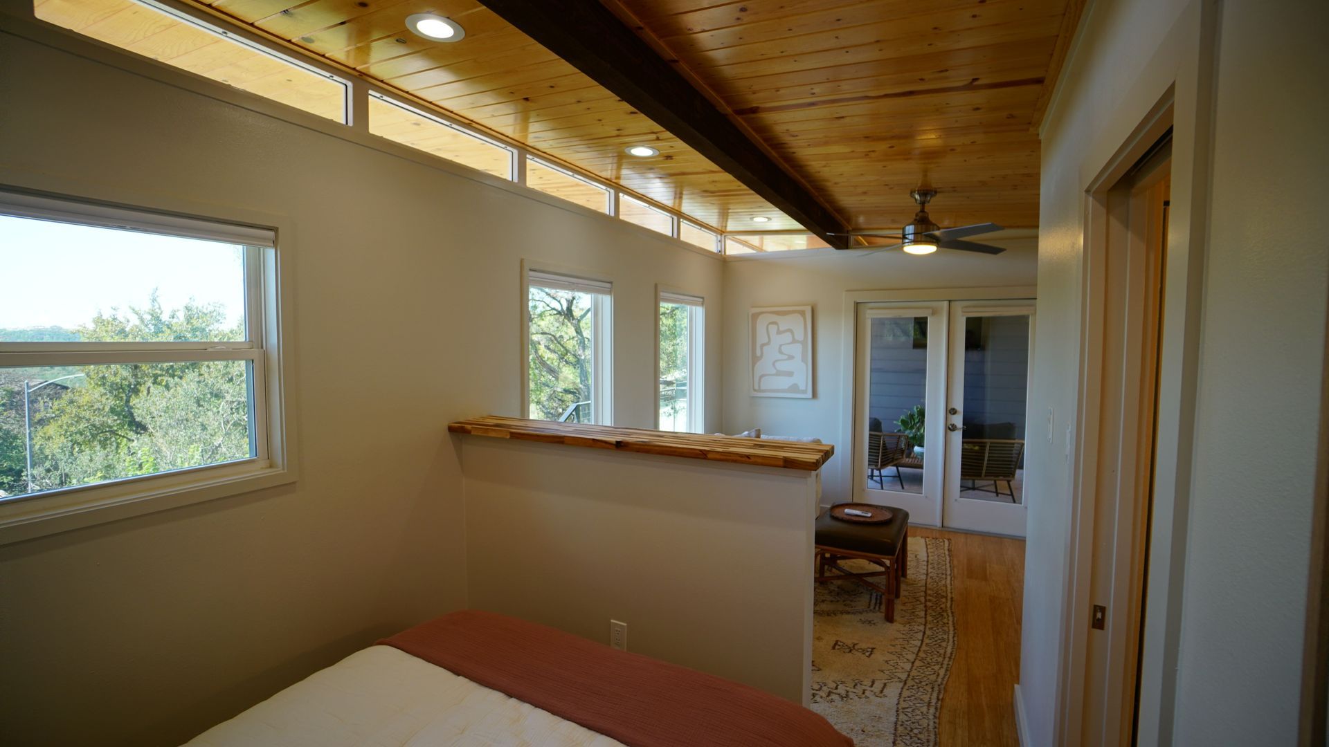 Bedroom with wooden ceiling, windows, and a doorway to a patio.