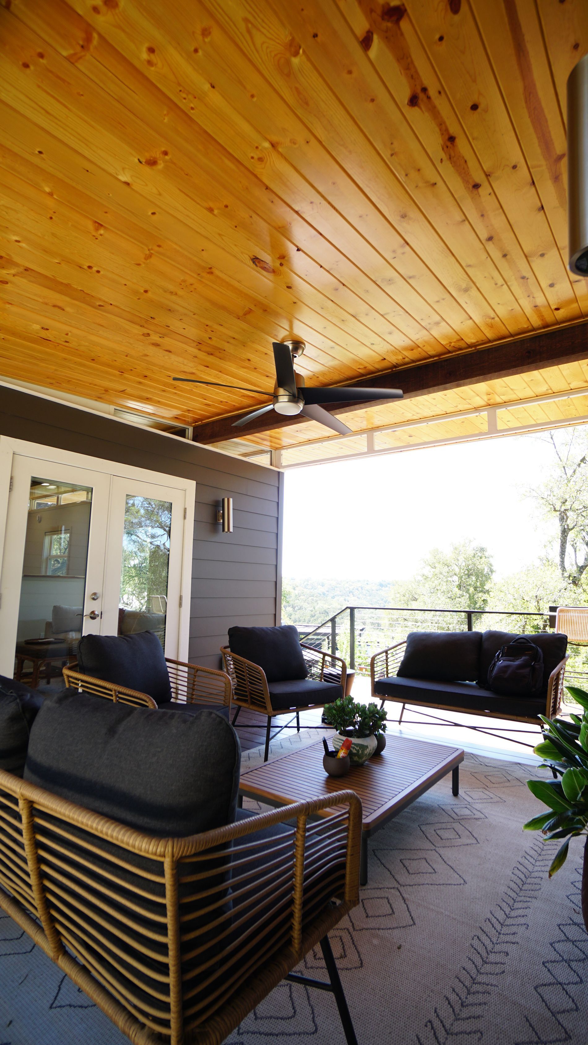 Covered outdoor patio with seating, wooden ceiling, and scenic view.