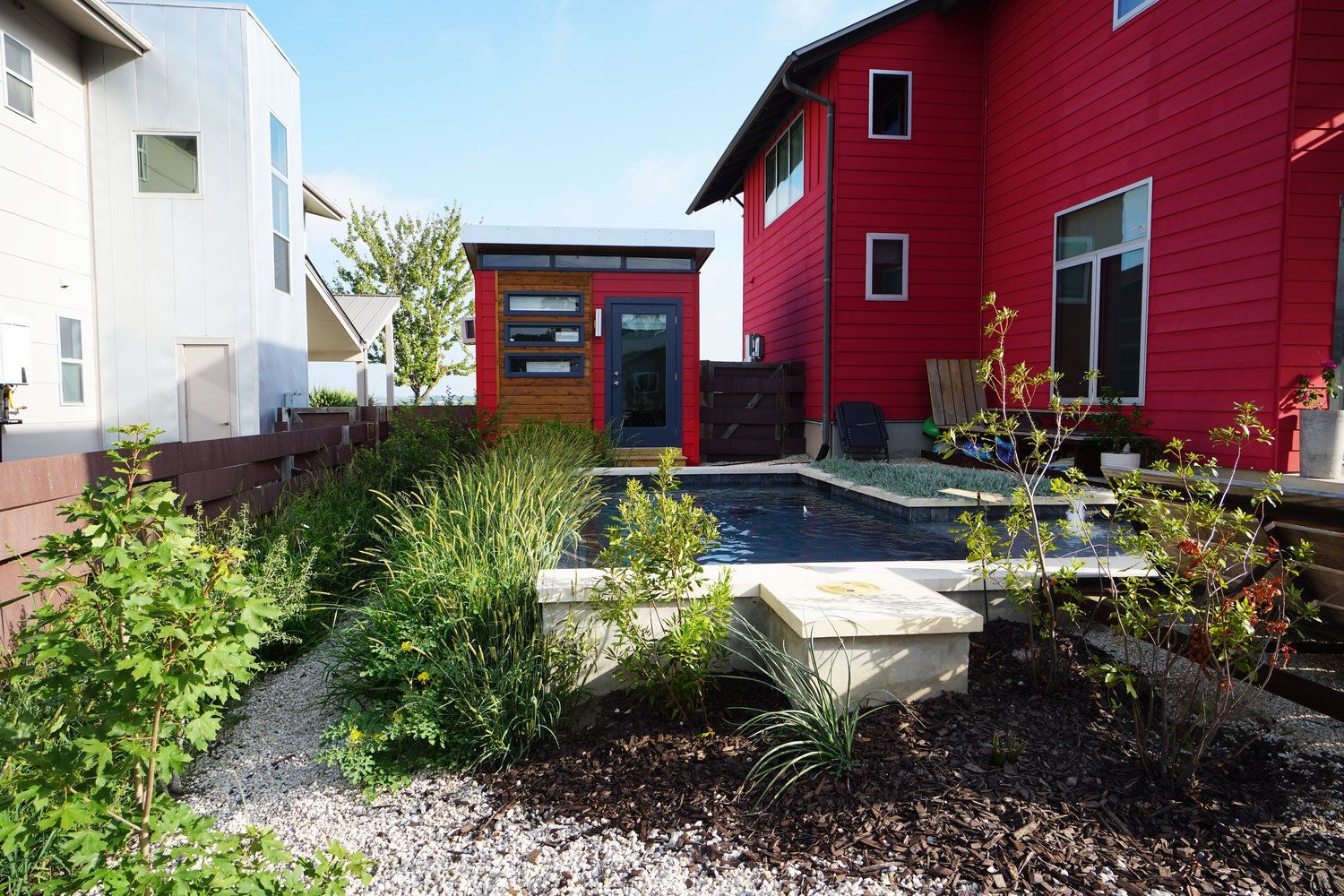 A red house with a pool in front of it