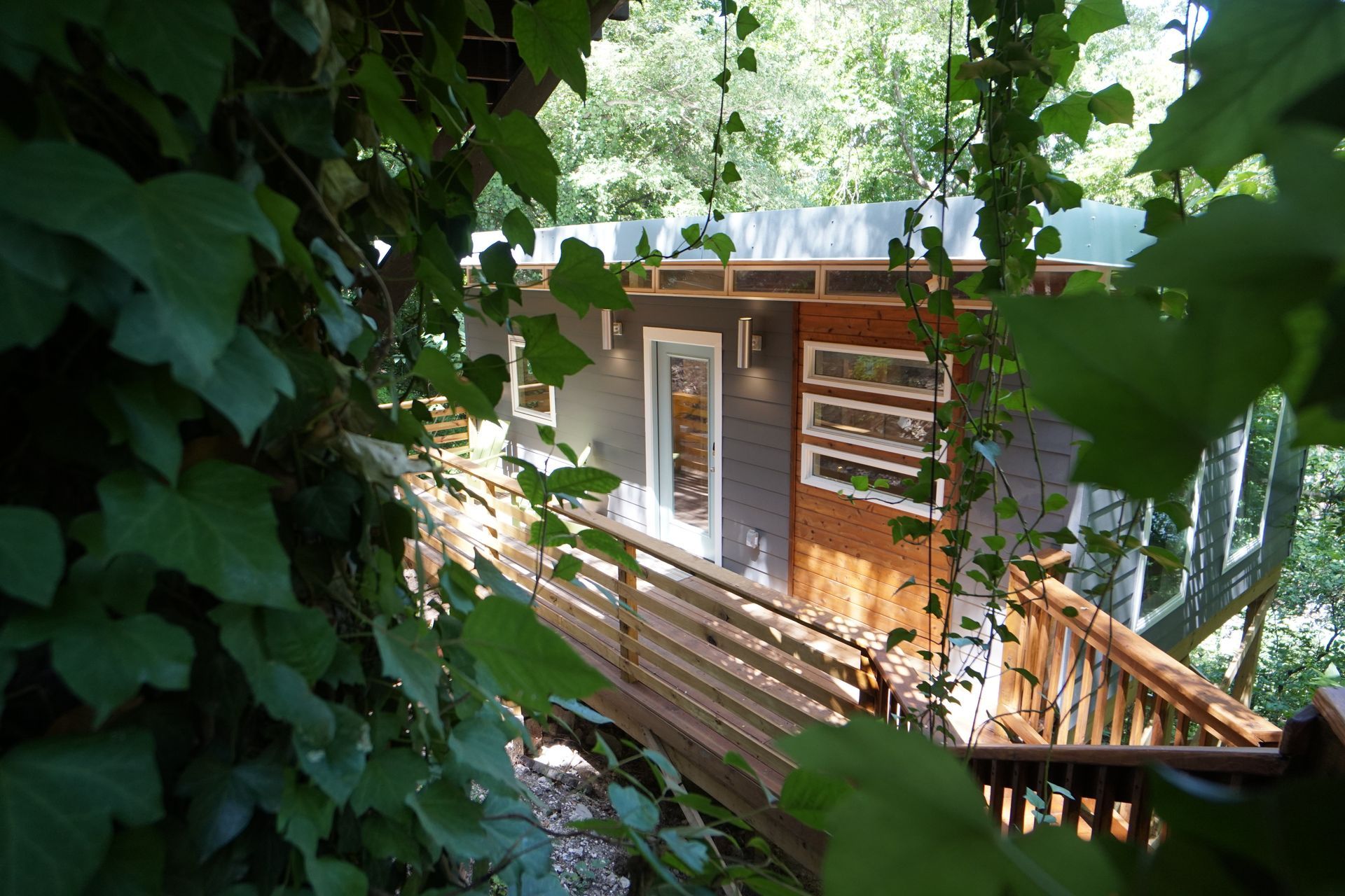 Treehouse with wooden deck, surrounded by trees and greenery.