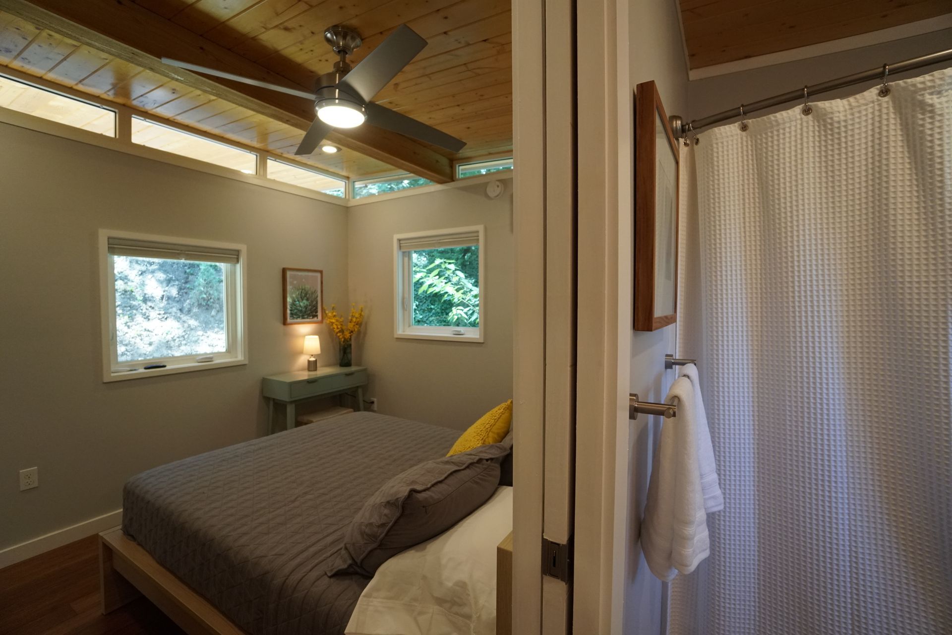 Bedroom with a bed, two windows, and a partially visible bathroom to the right.