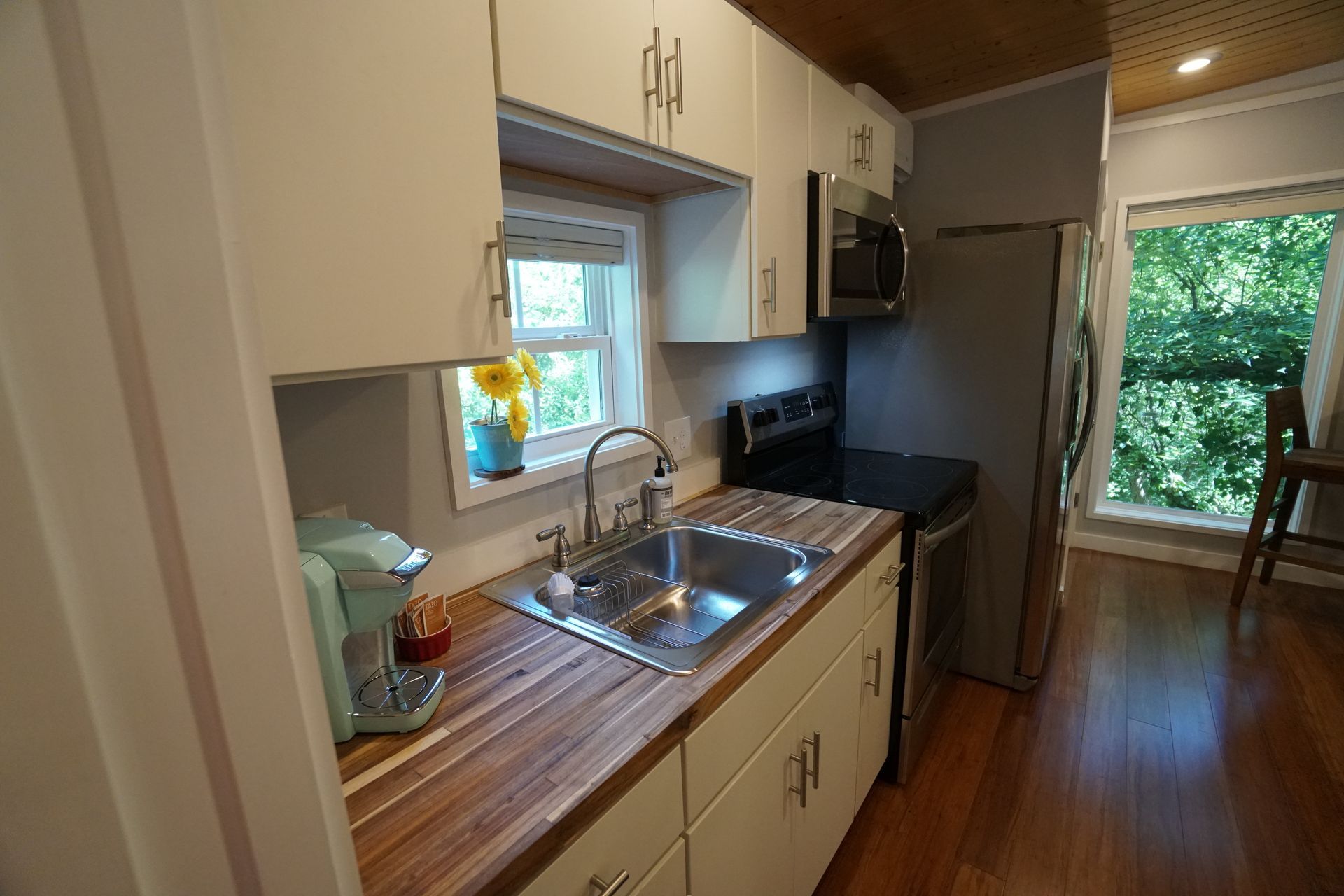 Small kitchen with white cabinets, stainless steel appliances, and wood countertops.