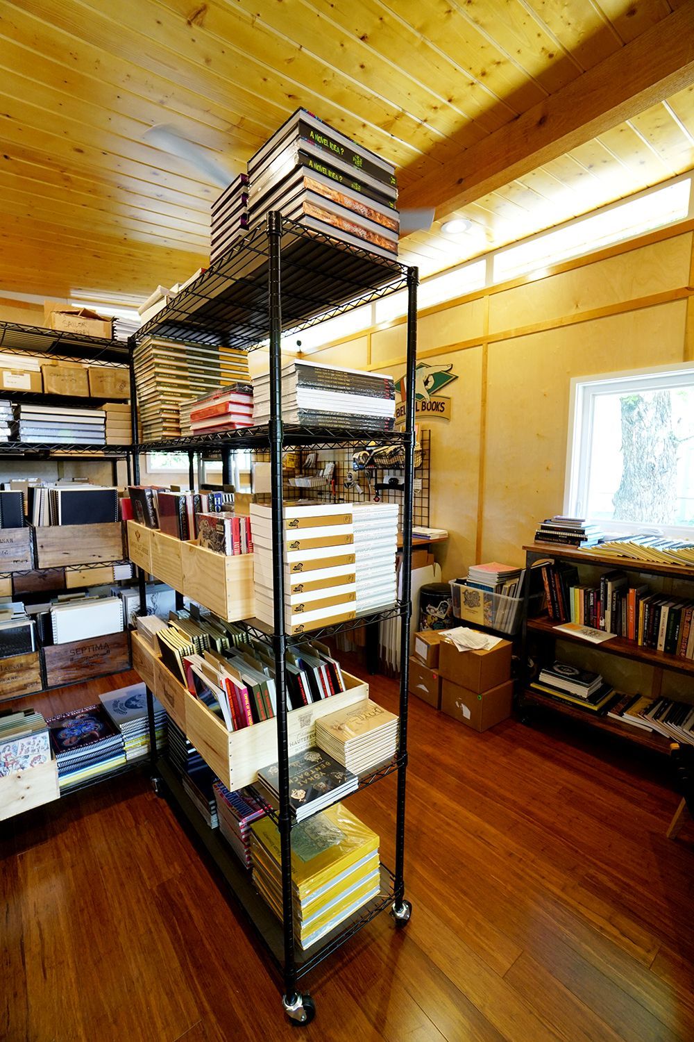 A room with shelves full of books and records, hardwood floors, and a wood-paneled ceiling.