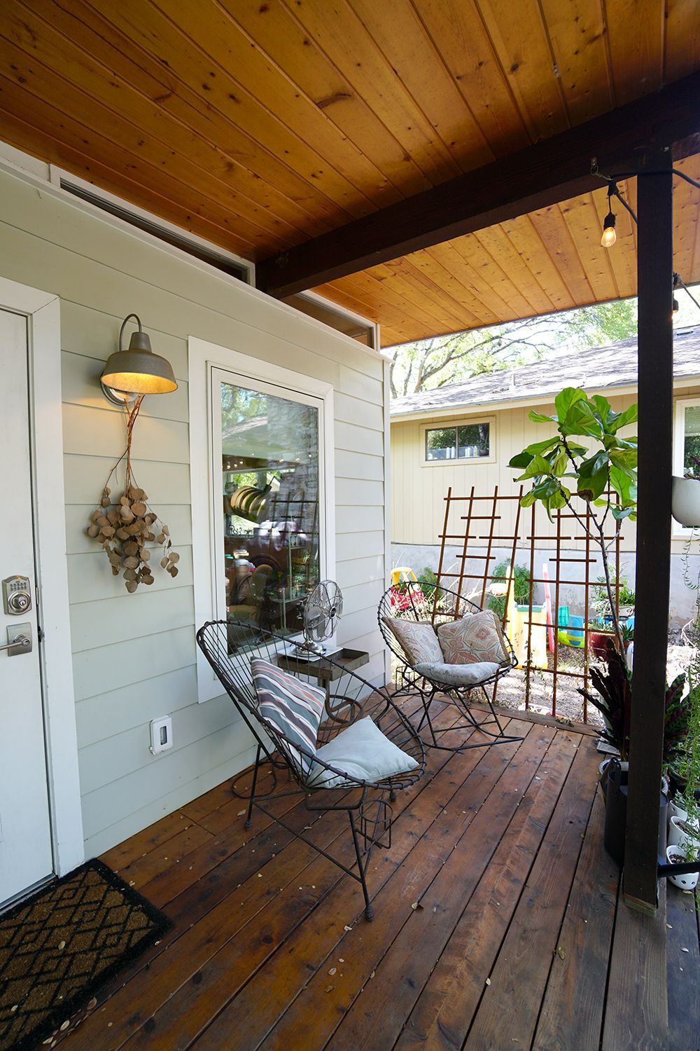 Cozy porch with seating, wood ceiling, and a view of a garden.