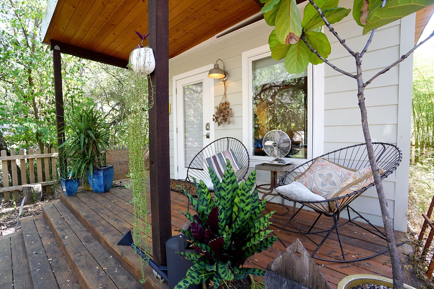 Cozy porch with rocking chairs, potted plants, and a small house; warm colors, wooden deck.